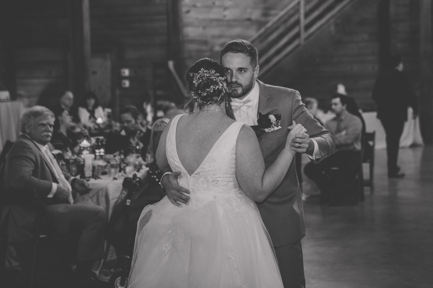 Wedding party members gather in a rustic wooden venue with natural lighting.