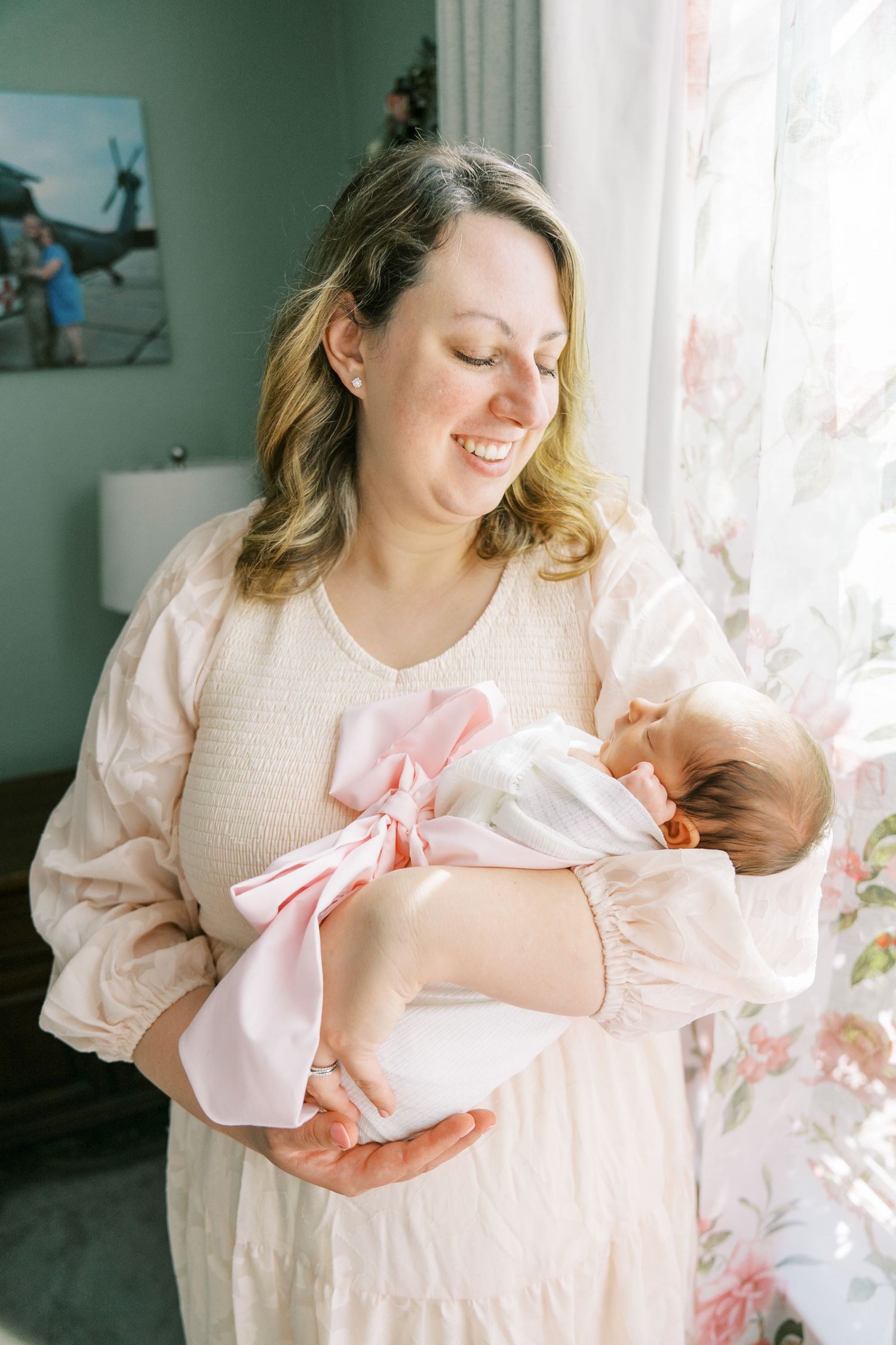 A tender moment between parent and newborn baby in a light-filled room with mint green walls.