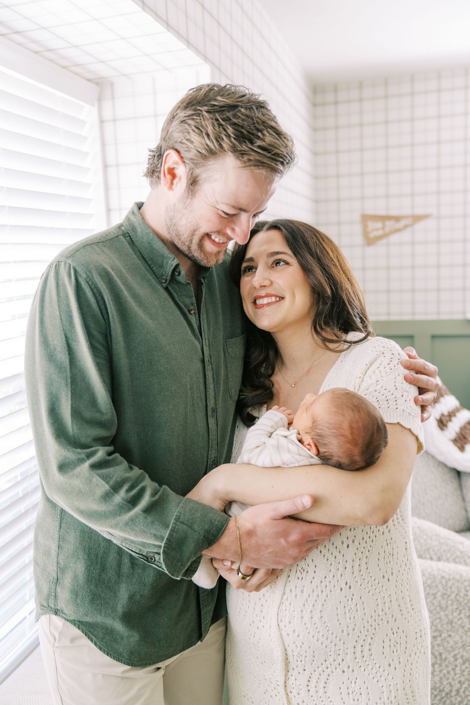 A tender family moment with a newborn baby in a bright white room.