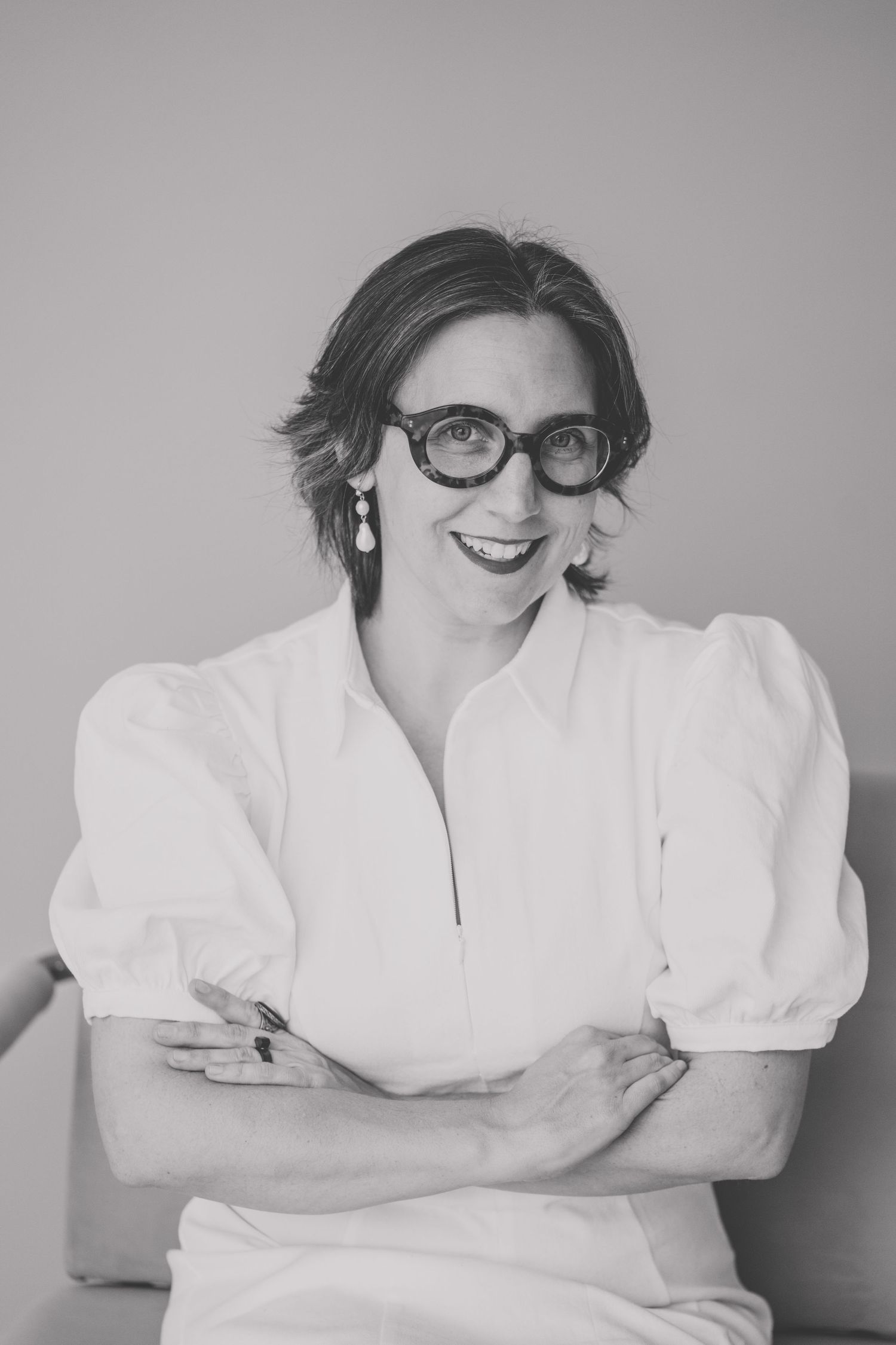Black and white portrait series showing relaxed poses in white blouse and vintage-style glasses.