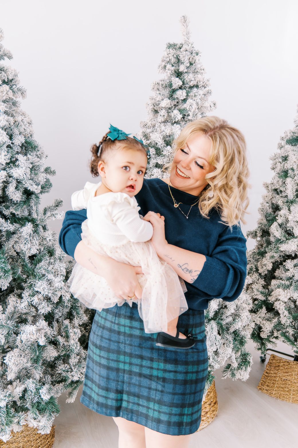A joyful holiday scene with a plaid skirt and white flocked Christmas trees in the background.