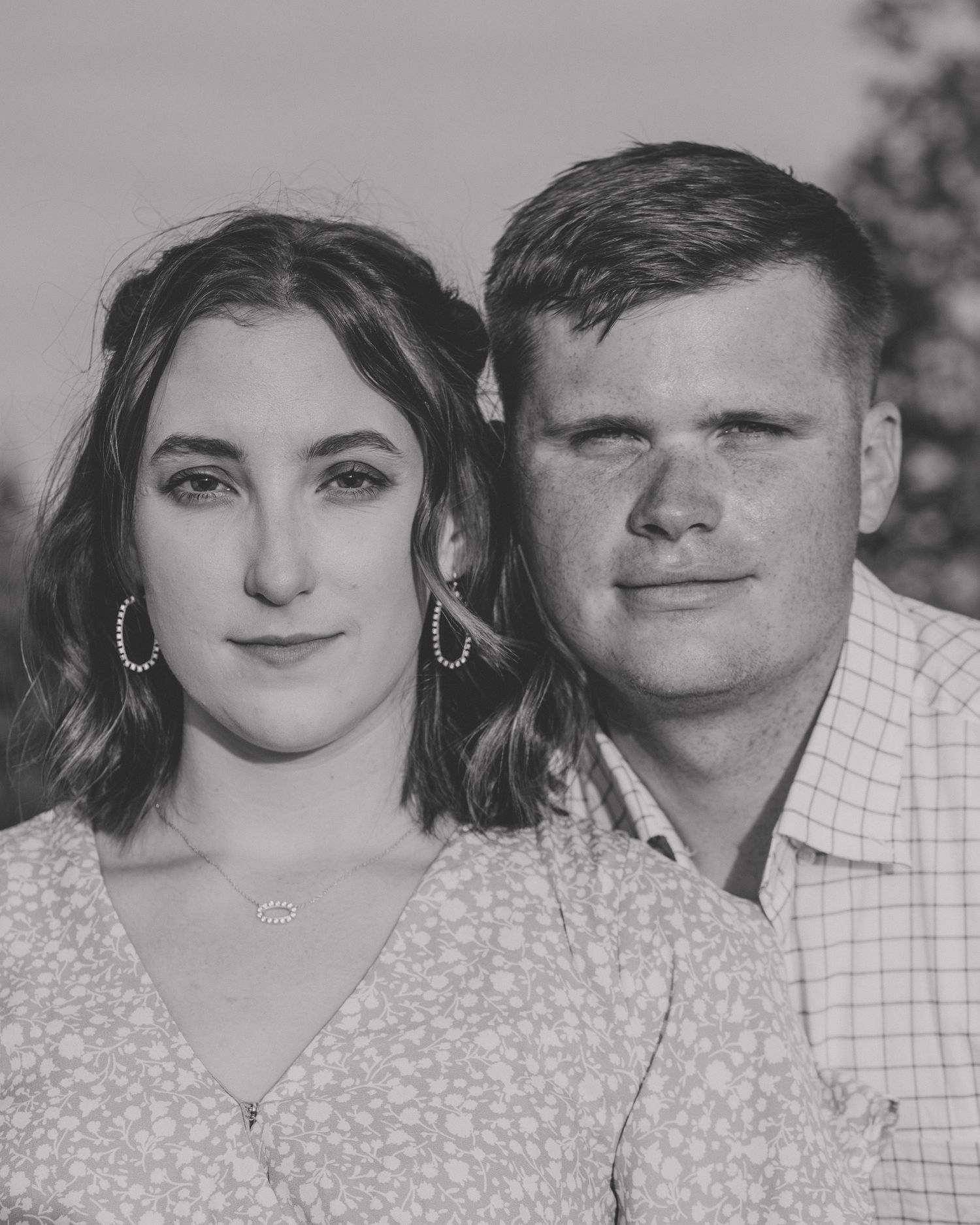 Black and white close-up portrait of a couple in casual attire against a blurred background.