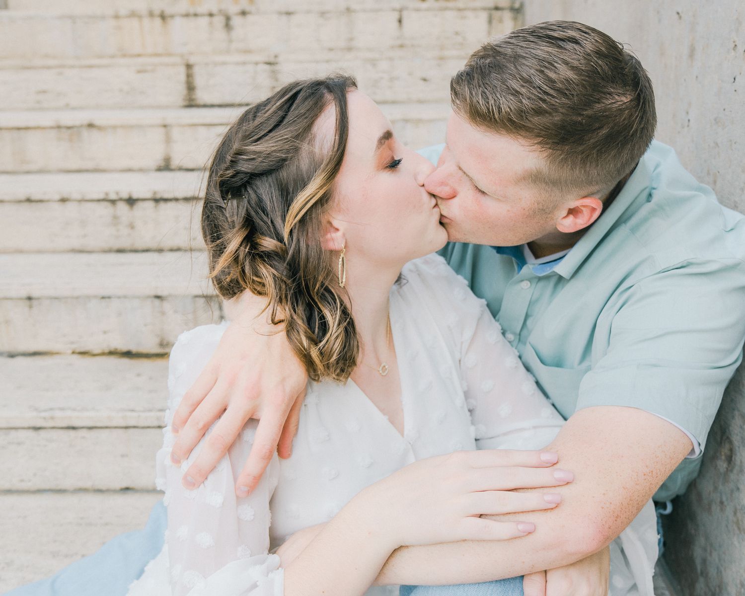 Romantic couple embracing and kissing in a series of tender moments against concrete wall.