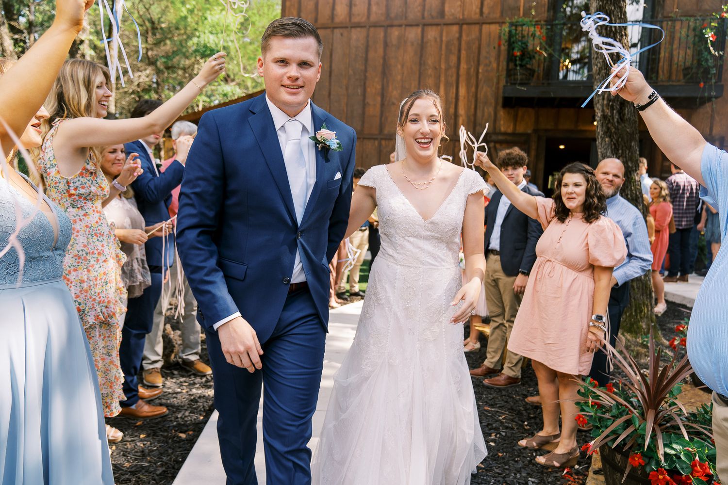 Joyful wedding party celebrates with champagne spraying in an outdoor garden setting.