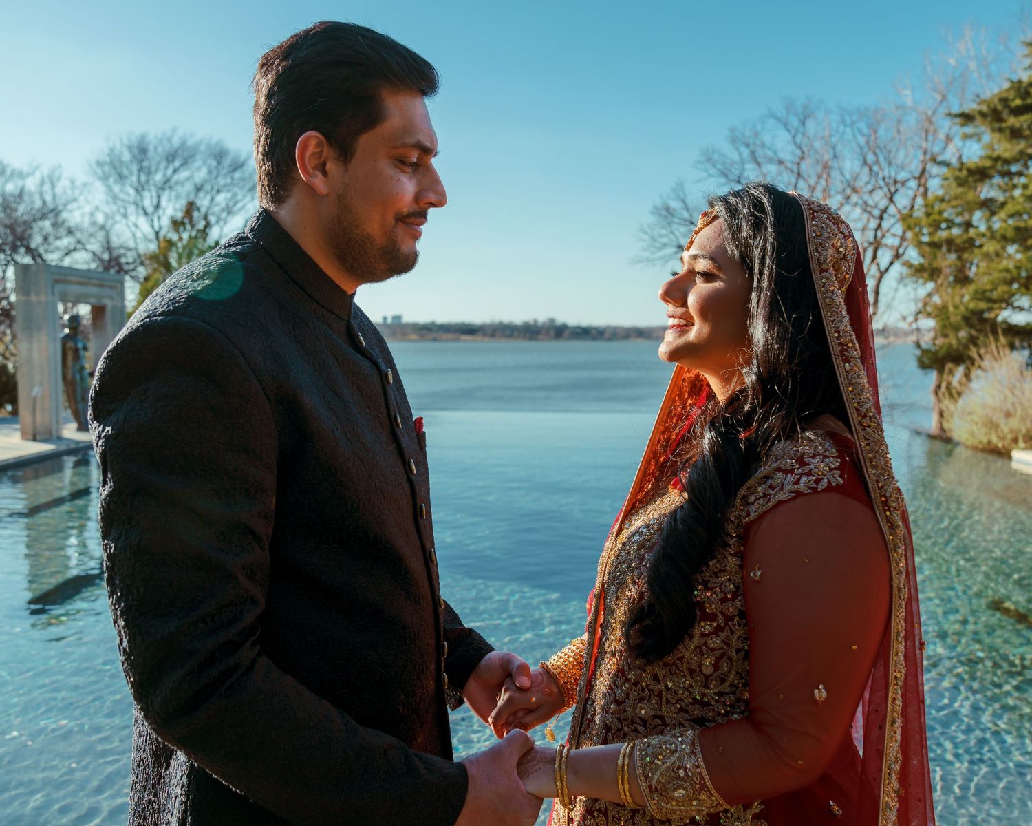 A series of romantic moments between a couple in traditional South Asian attire by a lakeside.