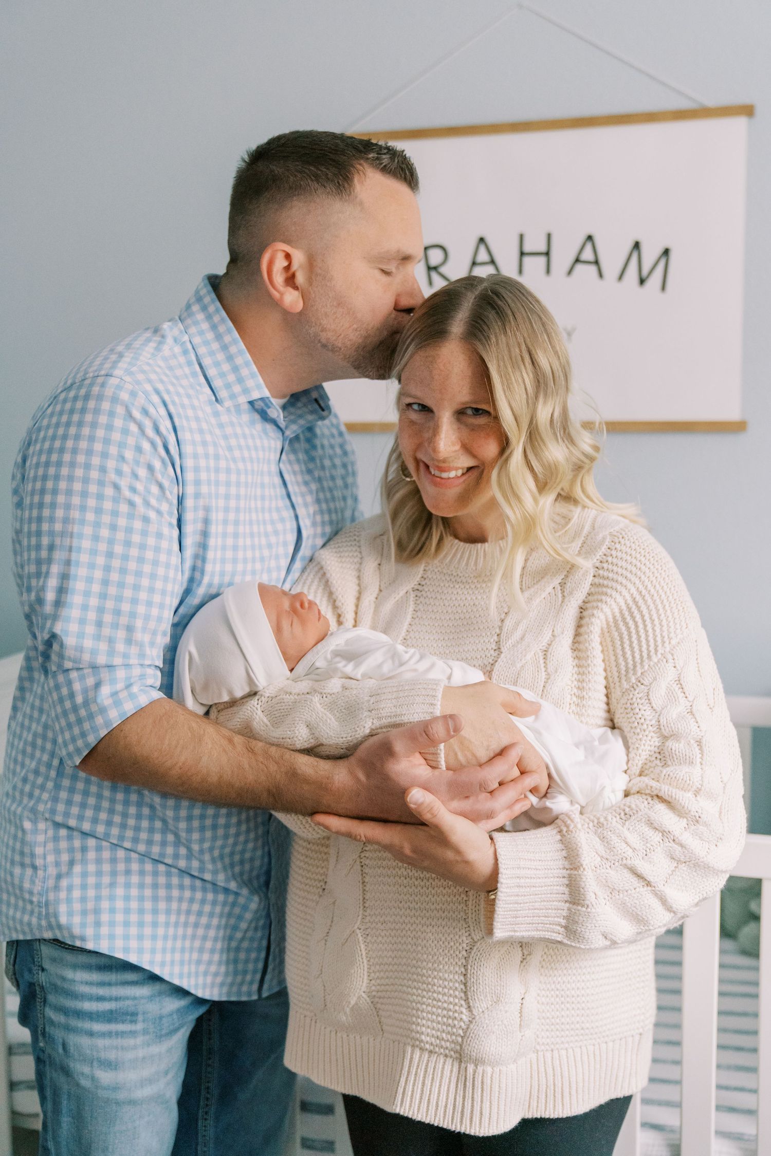 Family sharing intimate moments with newborn in nursery setting.