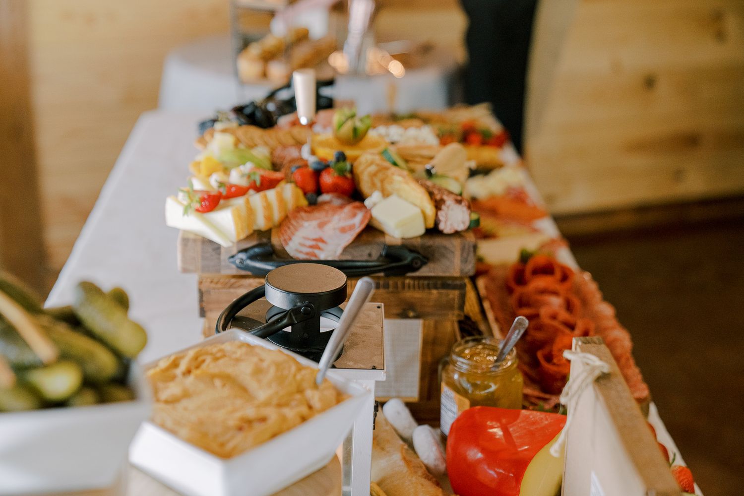 A rustic charcuterie board displays an assortment of meats, cheeses, and fresh vegetables on wooden serving platters.