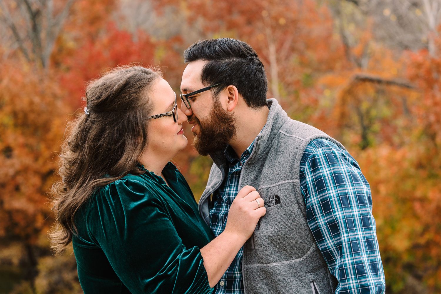 A romantic couple shares tender moments while walking along a wooded path in fall colors.