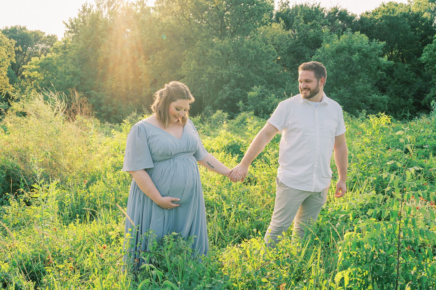 Golden hour maternity photography session in a field of vibrant yellow wildflowers.