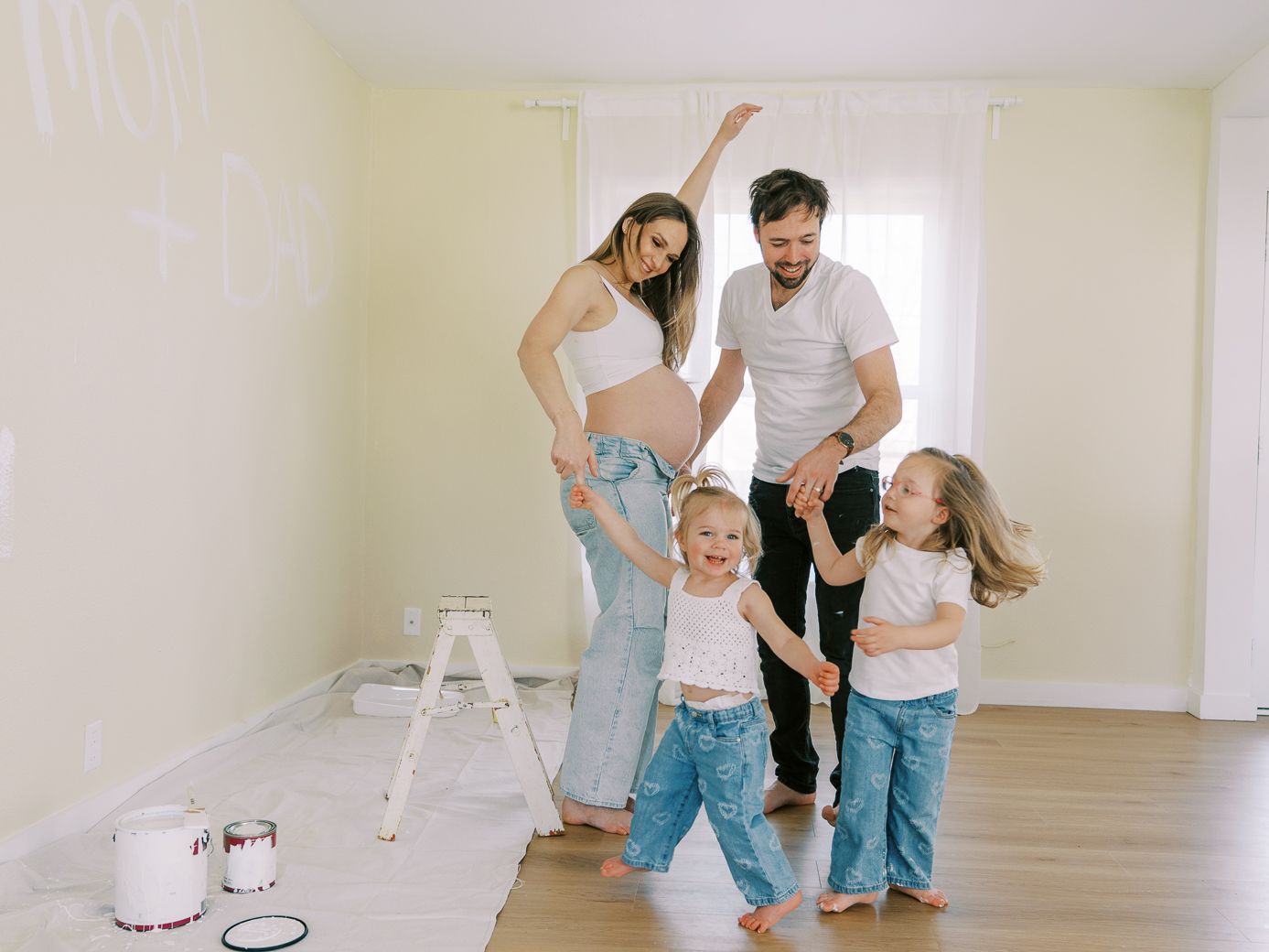 Family works together on home improvement project in empty room with white walls.