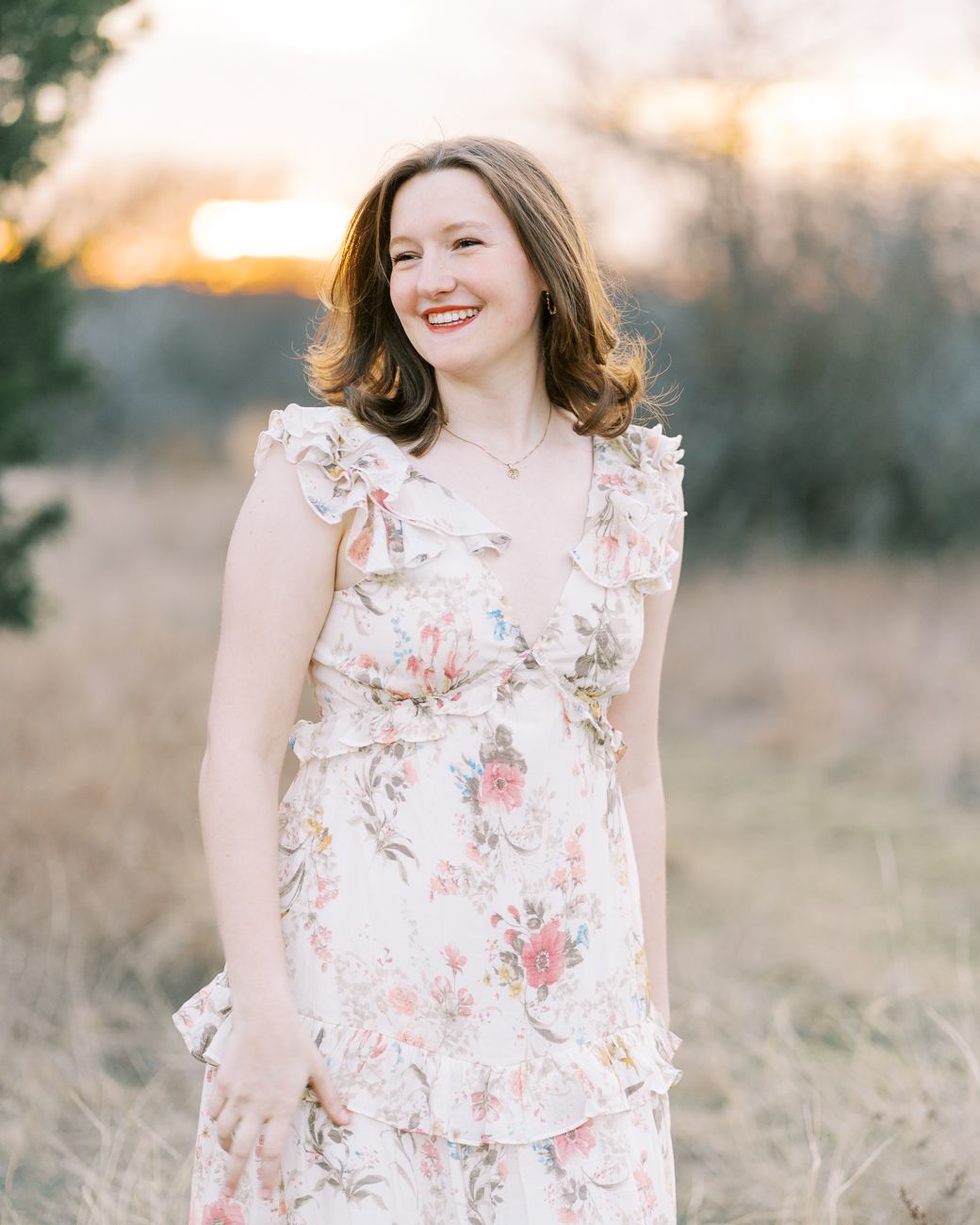 A soft floral dress is showcased against a natural outdoor backdrop during golden hour.