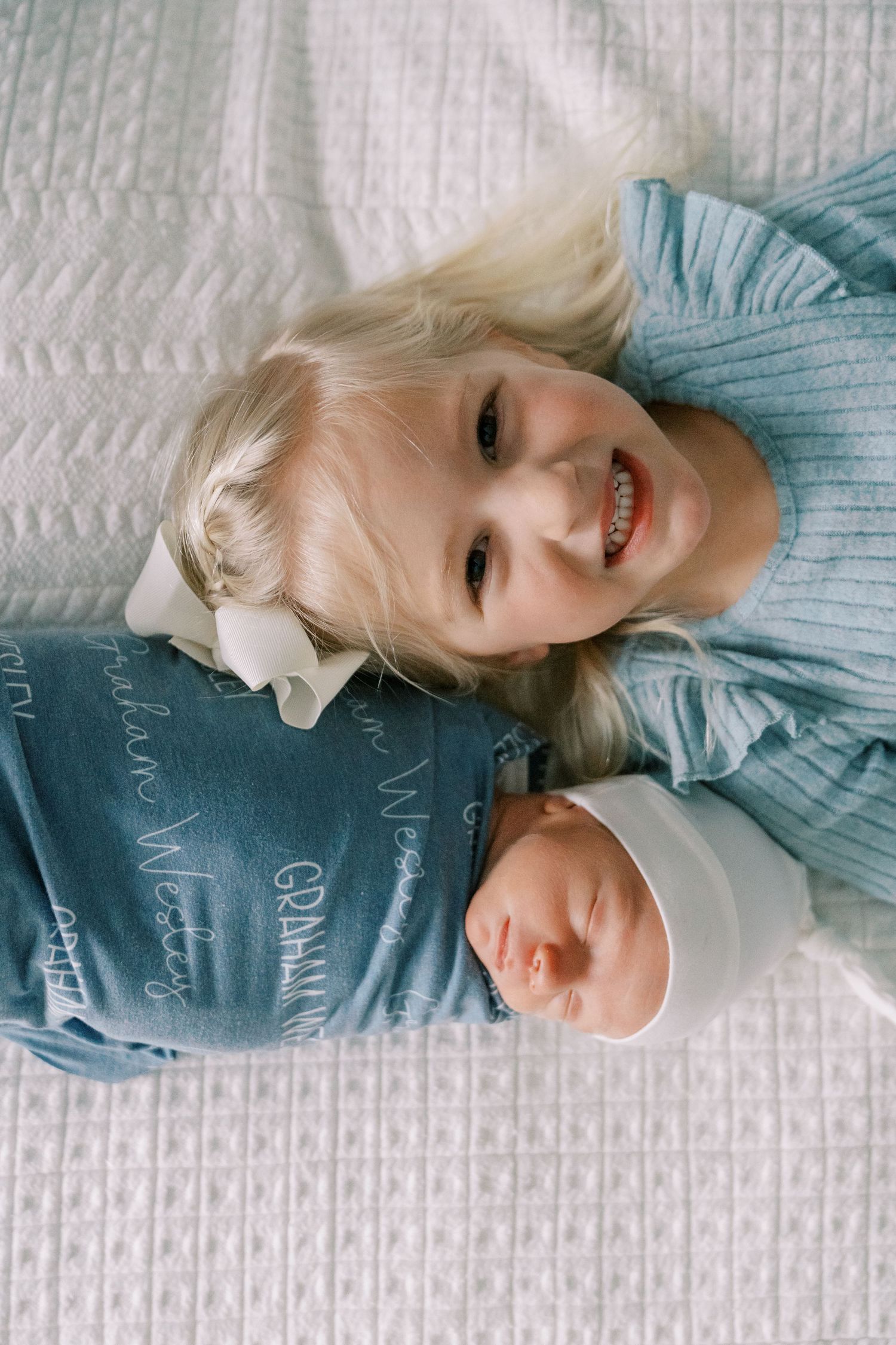 Close-up view of a baby resting on white textured bedding.