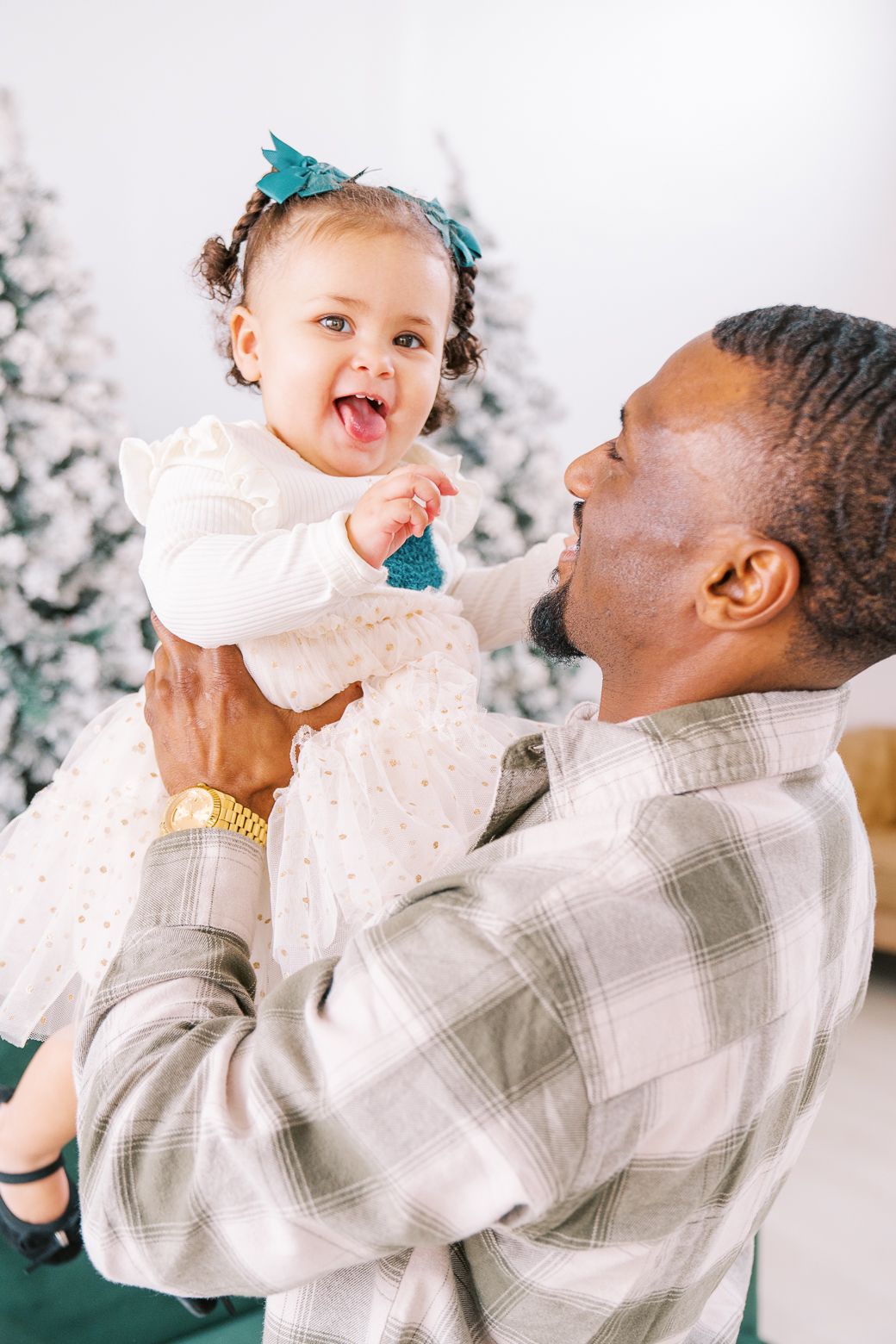 Playful holiday portrait session showing joyful moments against a backdrop of snowy Christmas trees.