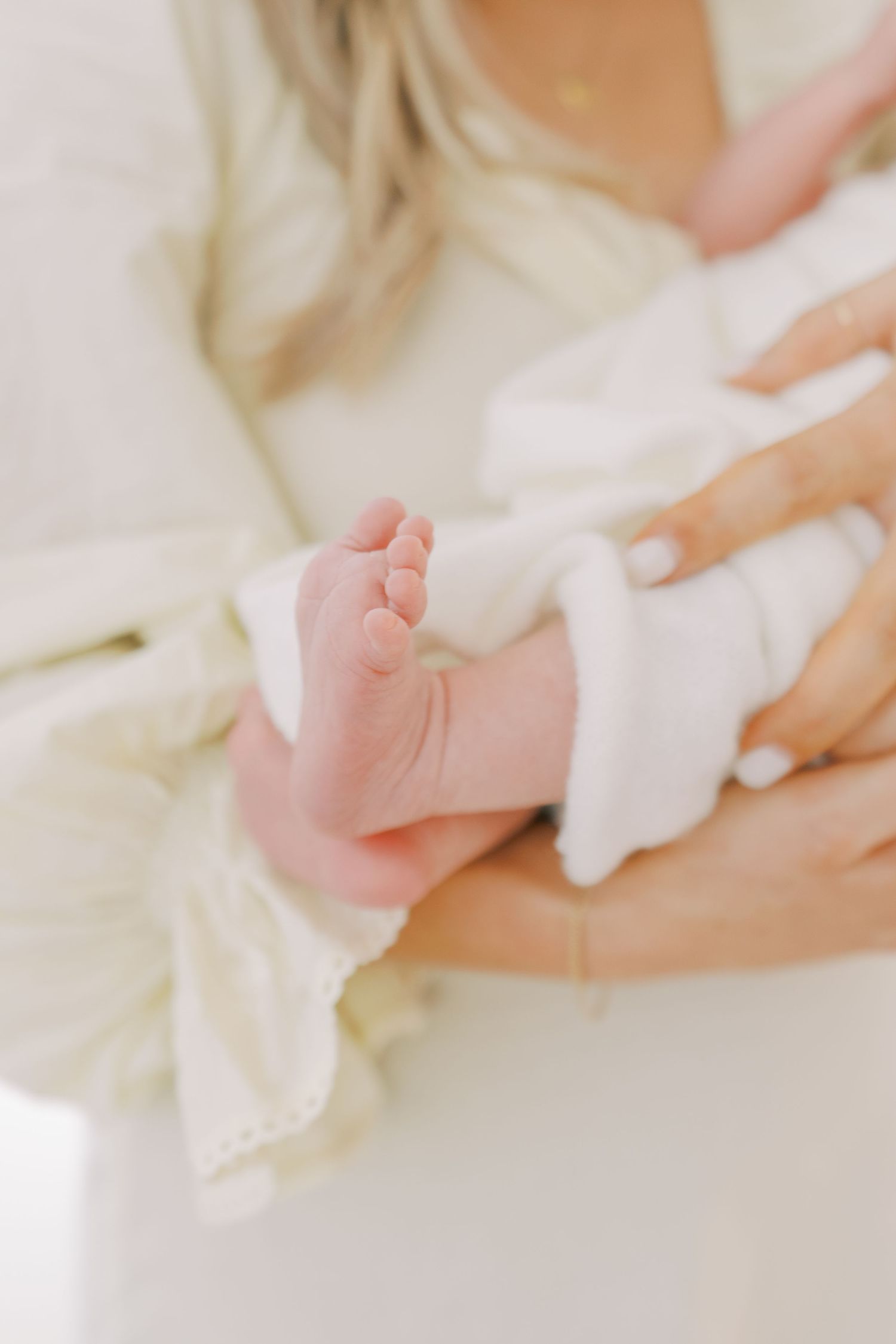 Close-up of tiny baby foot wrapped in soft white fabric showing delicate toes and skin.