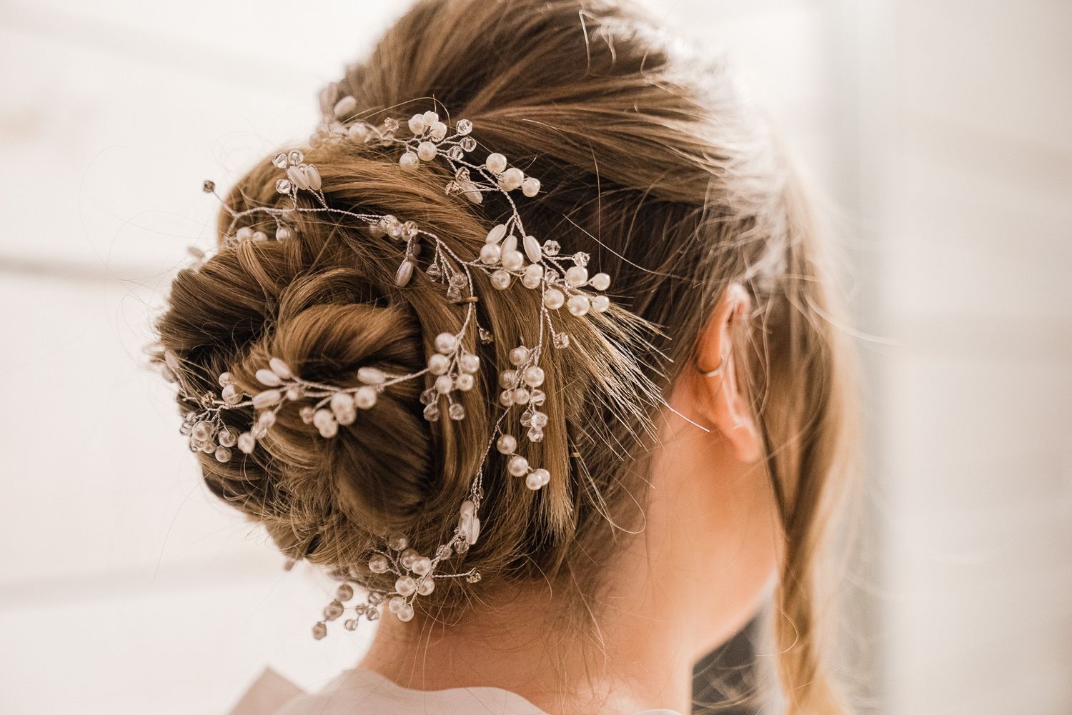 Delicate pearl and crystal hair accessories arranged in bridal updo hairstyle with soft romantic styling.