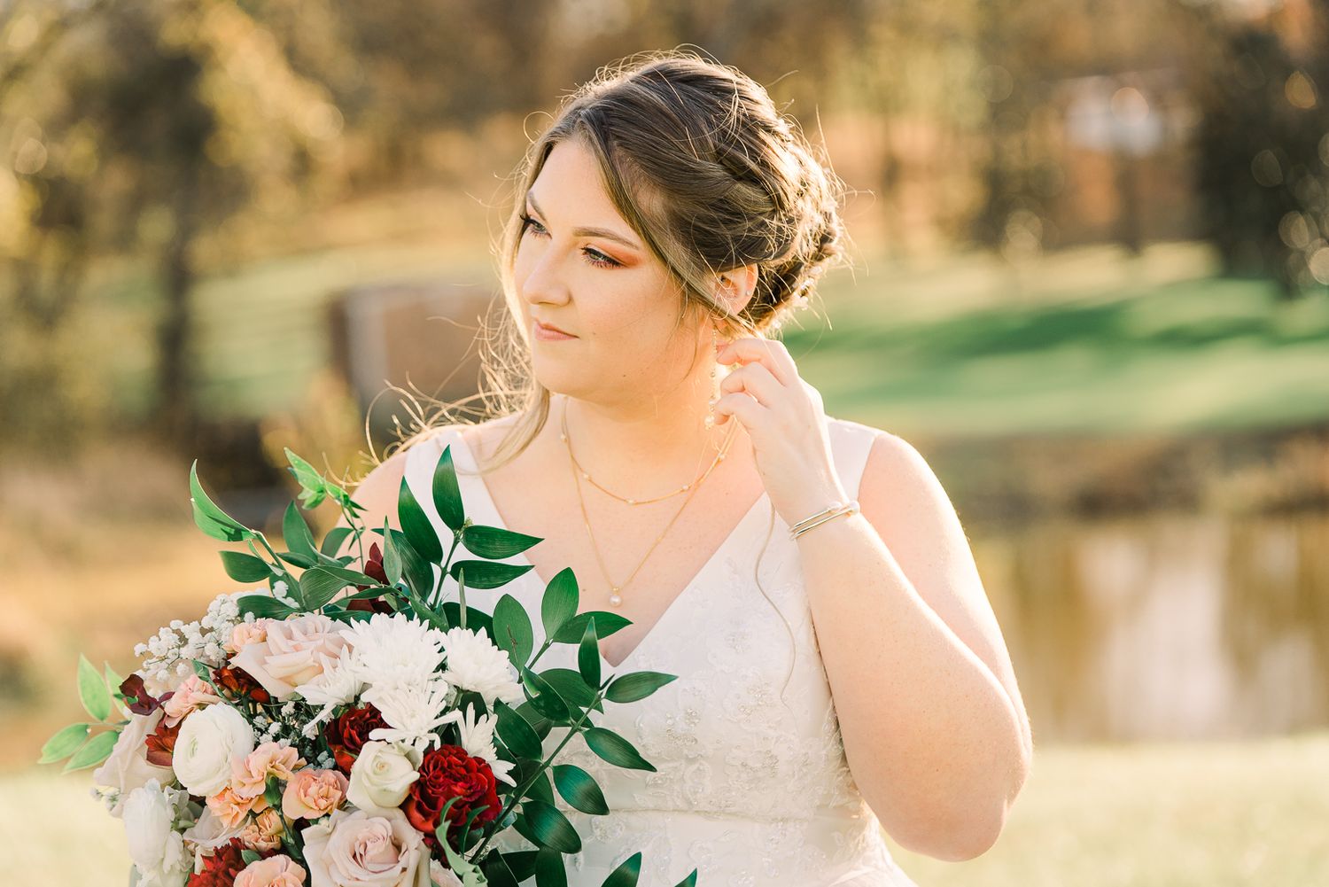 A romantic outdoor wedding photoshoot featuring a bride in a white dress holding a burgundy and blush floral bouquet.
