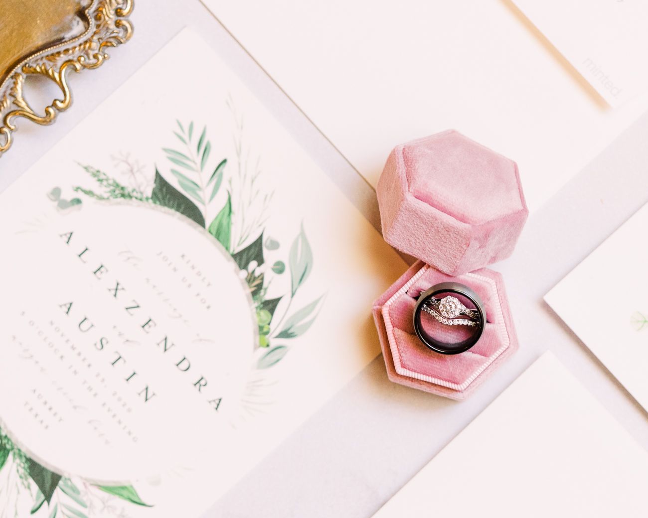 Pink hexagonal ring boxes with delicate jewelry and botanical decorative elements arranged on a light background.