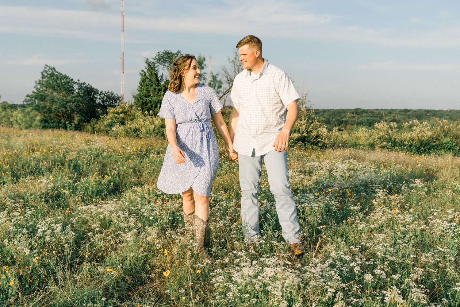 A couple dances together in a sunlit meadow filled with wildflowers on a summer afternoon.
