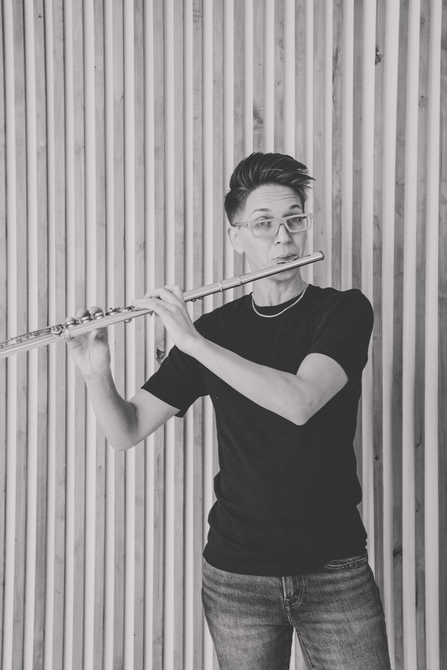 Black and white photo of someone playing flute in three different poses against a striped background.