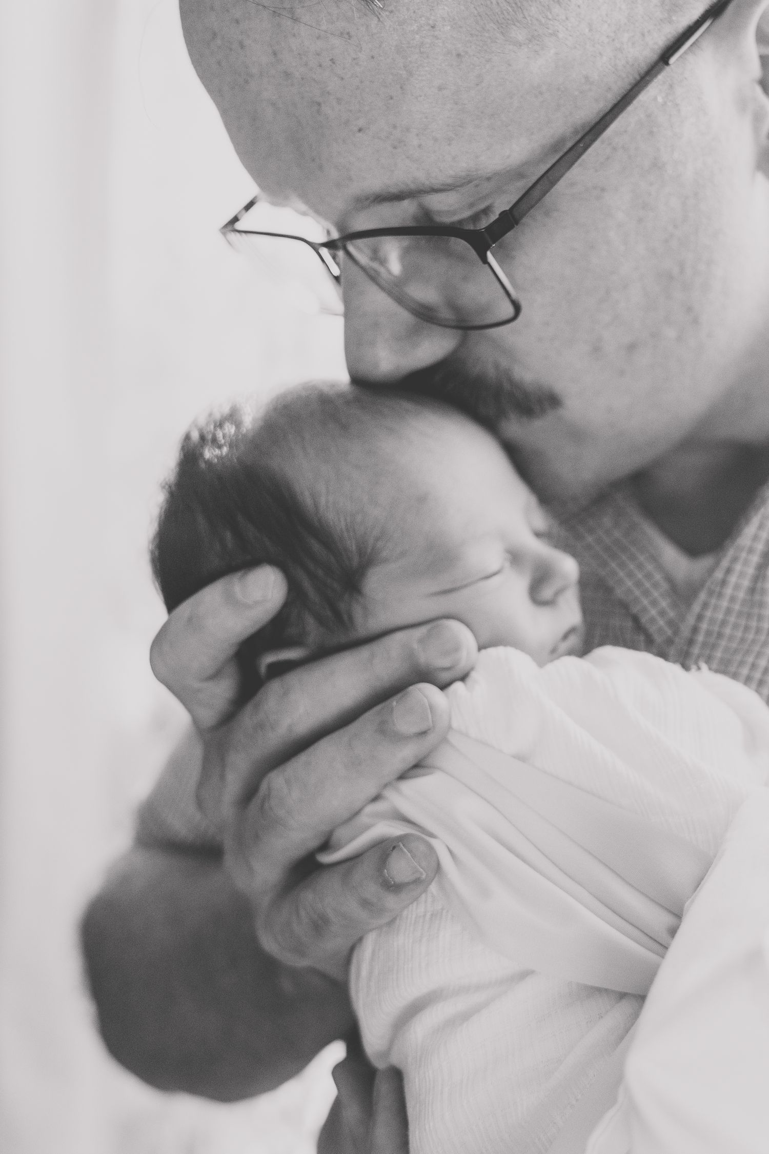 Series of intimate black and white photos showing tender moments with a sleeping newborn.