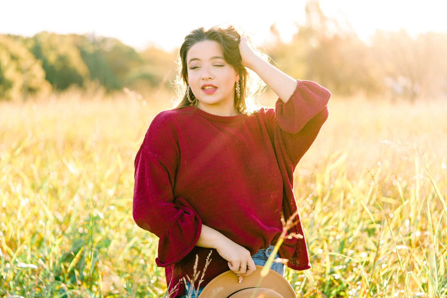 Figure in maroon top enjoys a carefree moment in sun-drenched field of wheat.