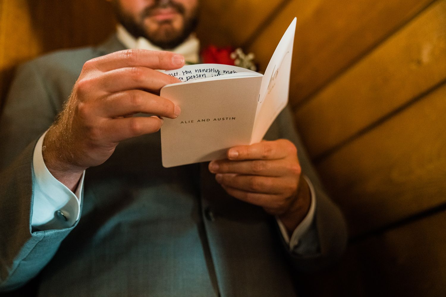 Wedding party members in gray suits read from small cards during an outdoor ceremony.