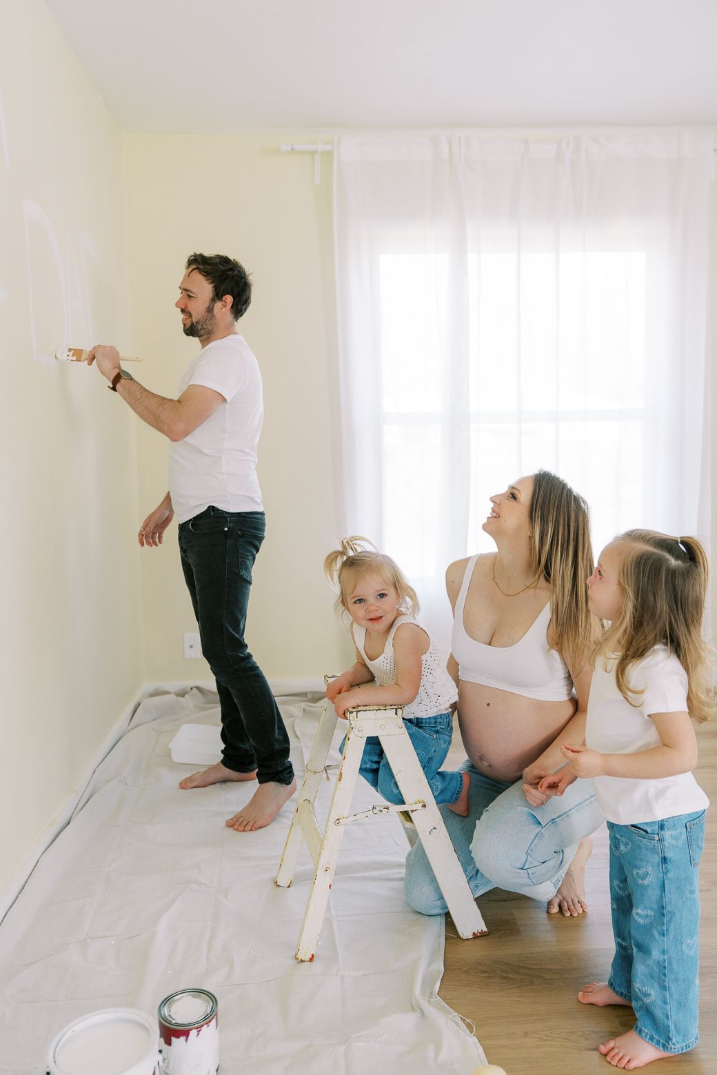 A playful family moment captured in a bright minimalist room with white walls.