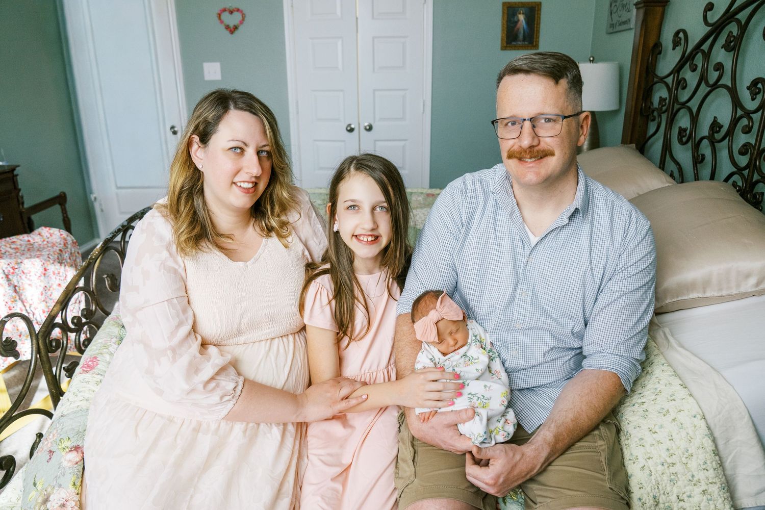 Family portrait series in a mint green room showing tender moments with a newborn.