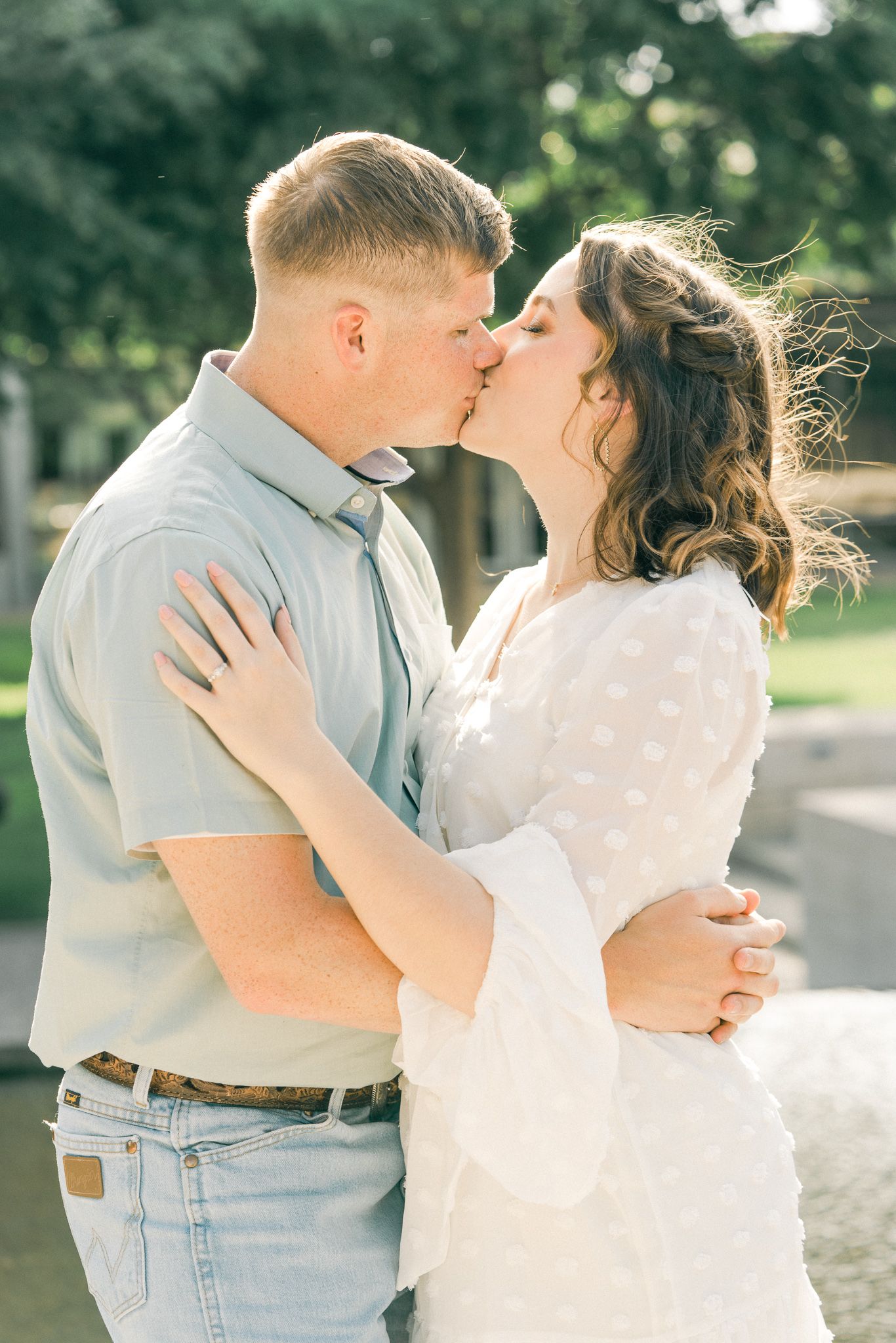 Romantic couple in casual attire sharing tender moments in an outdoor setting with natural lighting.