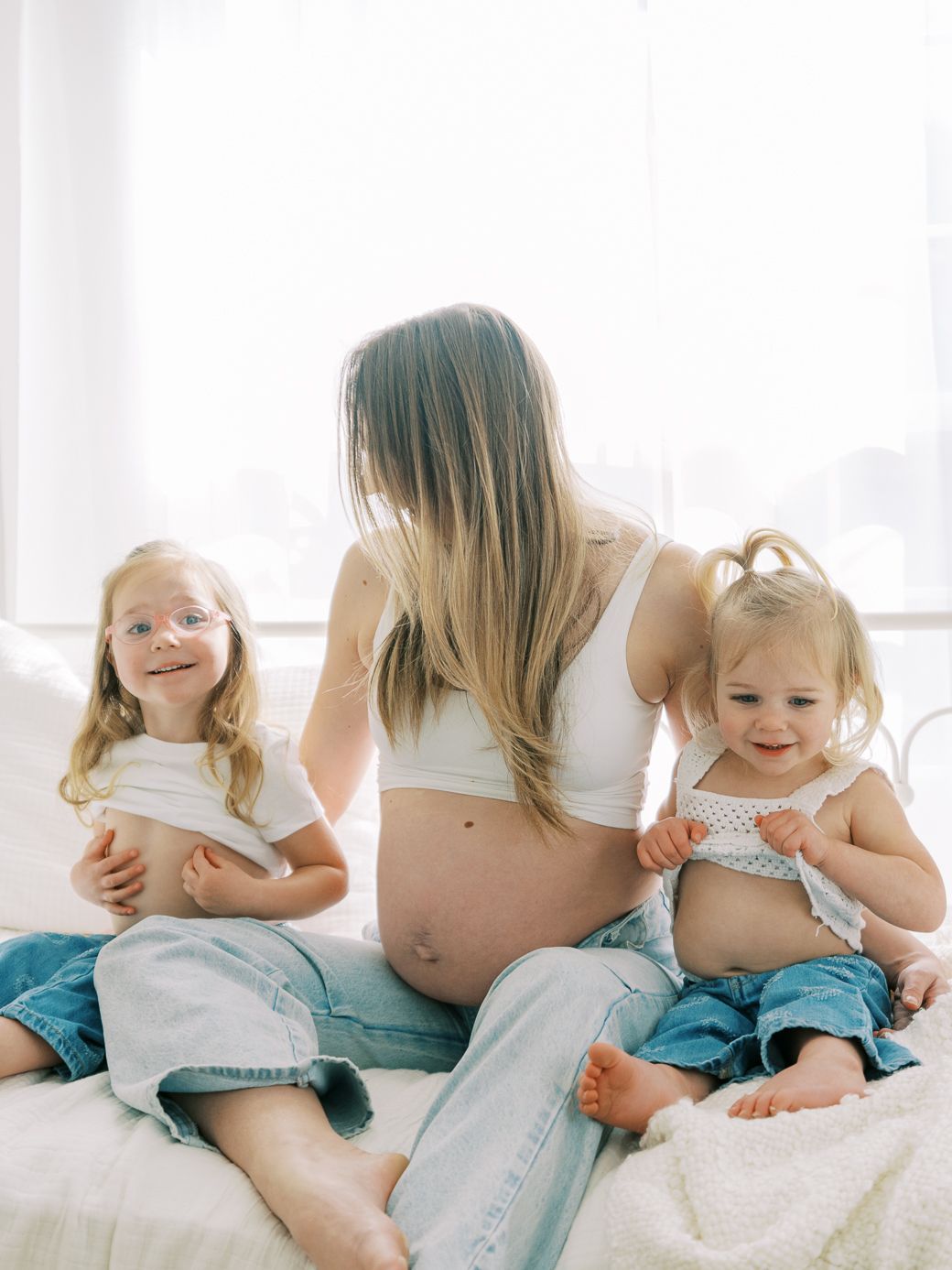 A series of candid moments showing a baby and parent sitting together on a white bed in matching blue outfits.