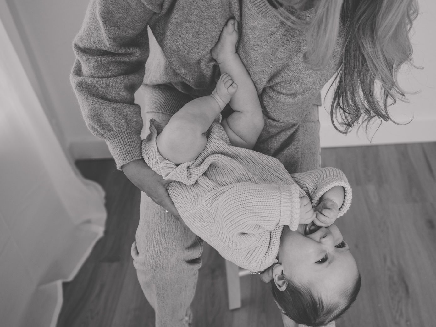 Black and white image of mother and baby bonding on bed with natural lighting.