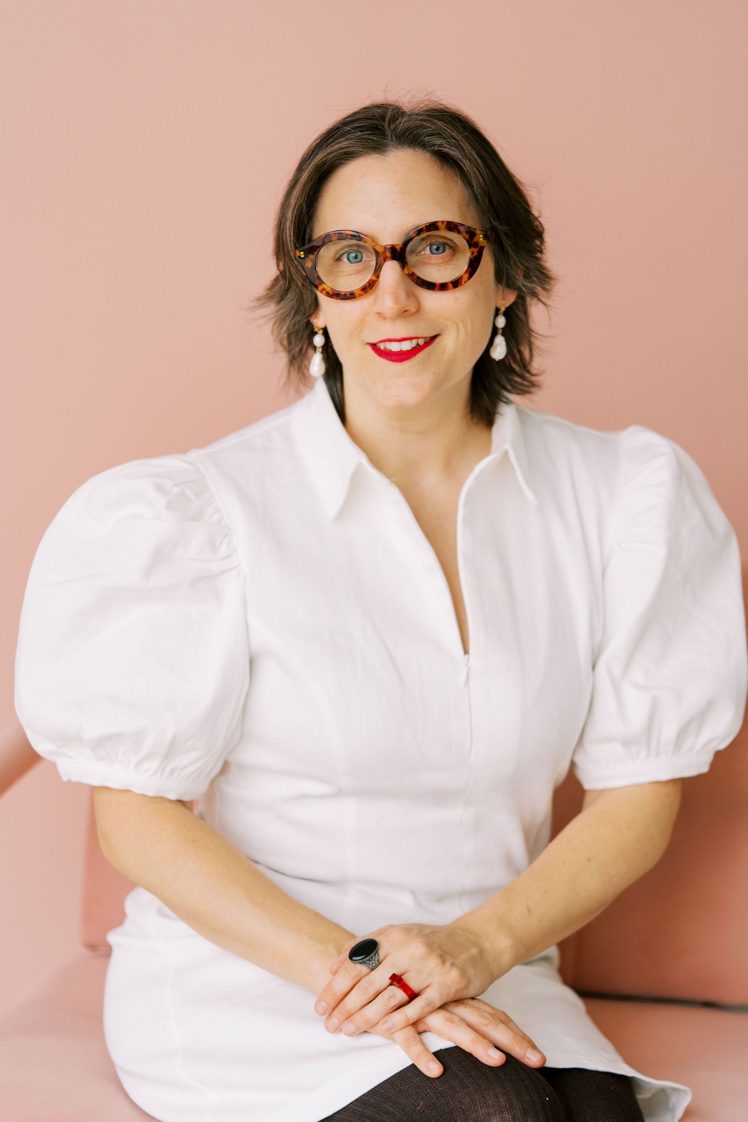 Professional portrait series featuring a person in a white button-down shirt with puff sleeves against a pink backdrop.