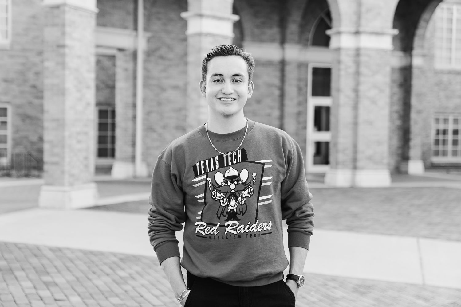 Black and white portrait of someone posing in front of historic brick architecture.