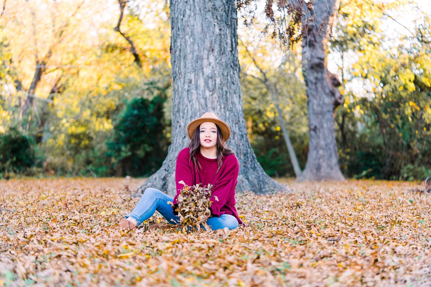 A series of autumn photos showing someone lying in colorful fallen leaves during a fall photoshoot in a park.