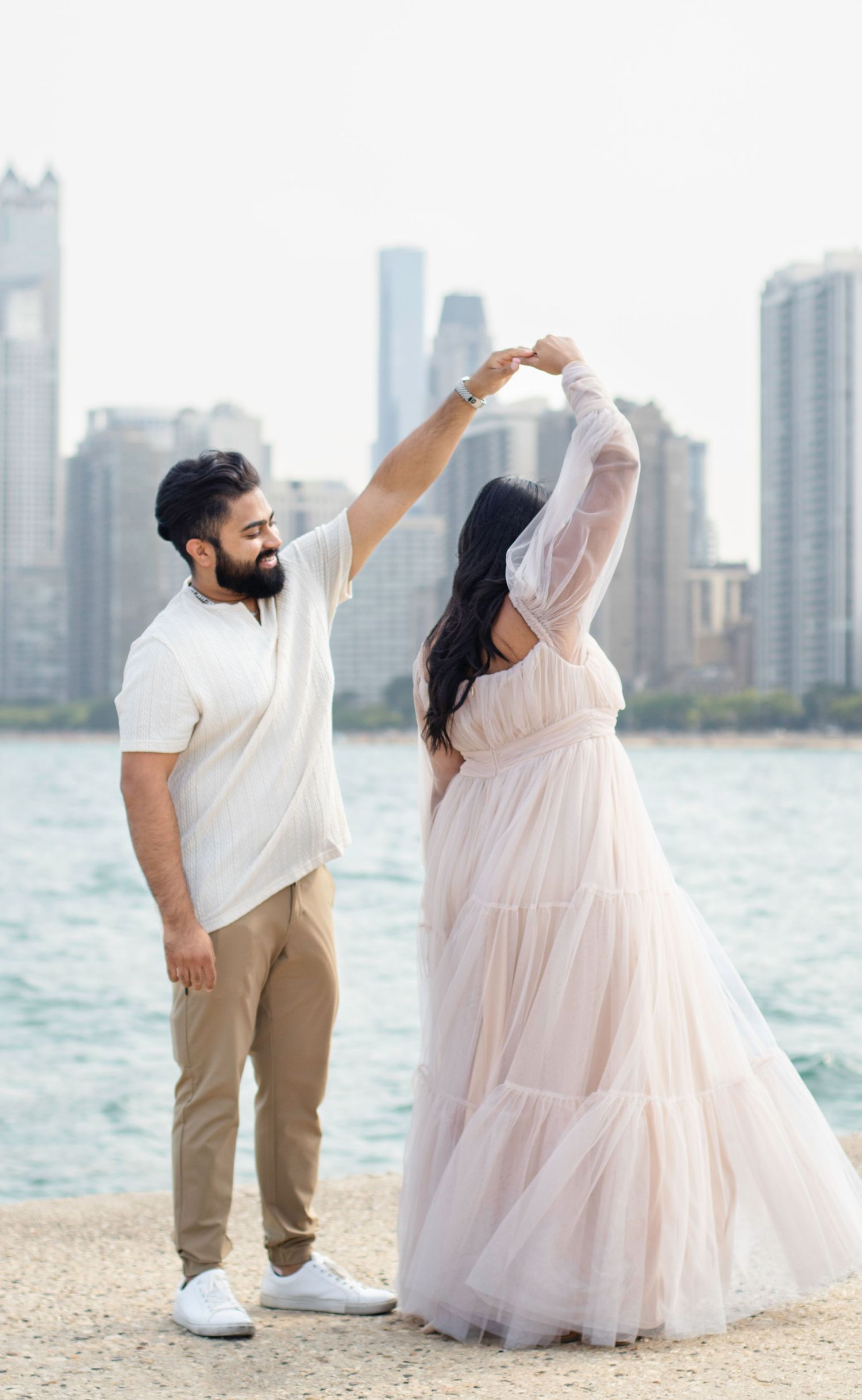 Couple dancing on beach with Chicago skyline in background during sunset photo session.