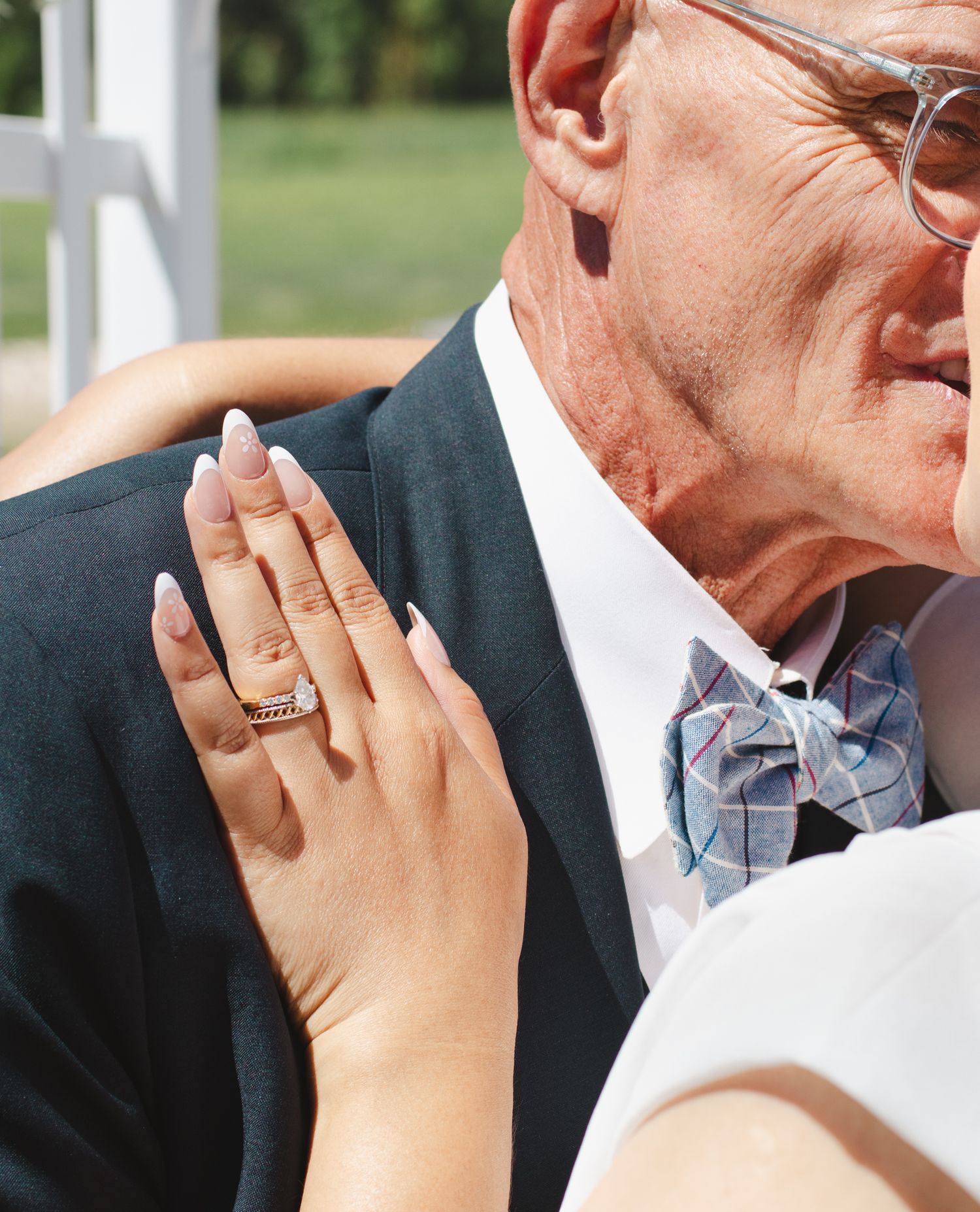 Close-up emotional wedding moment captured under floral arch outdoors.