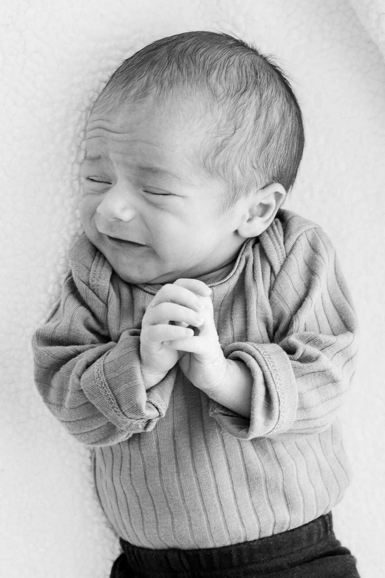 Black and white portrait series showing a baby's joyful expressions while wearing a knit sweater.