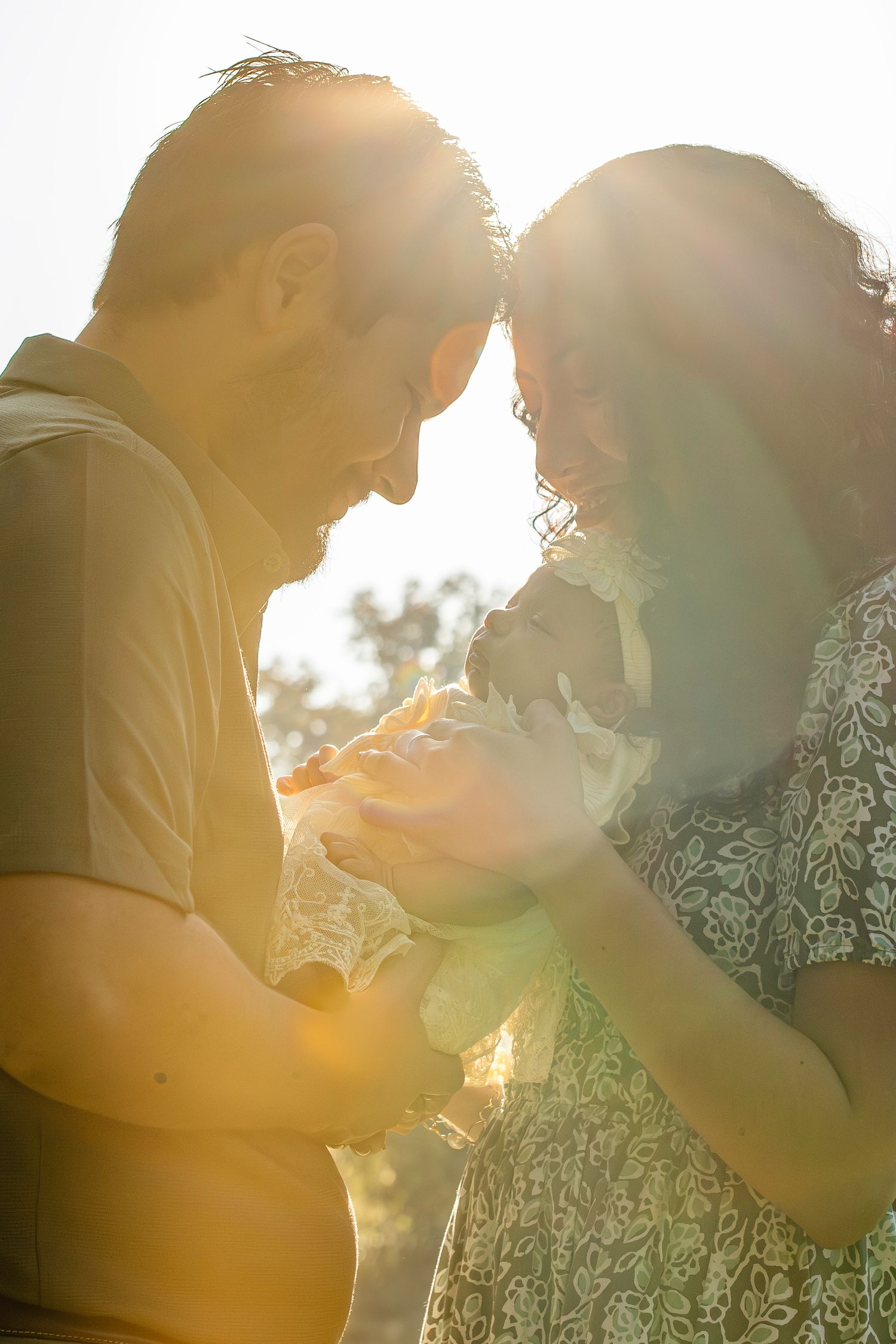 A couple embraces in warm golden sunlight filtering through trees creating a romantic silhouette effect.