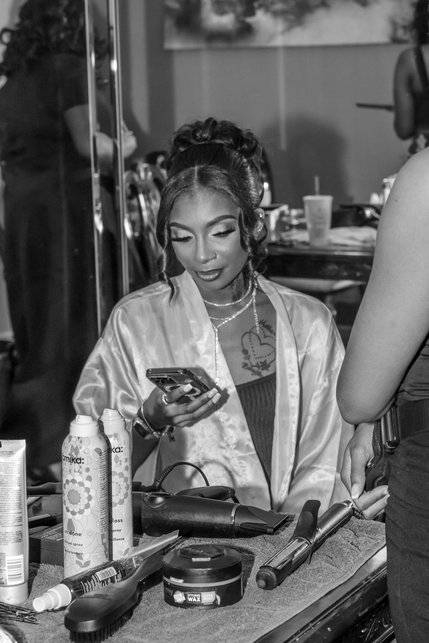 Black and white photo showing water bottles and makeup supplies on a dressing room table.