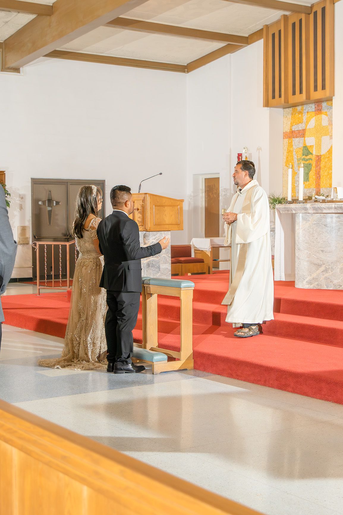Couple exchanges vows before priest at church altar during intimate wedding ceremony.