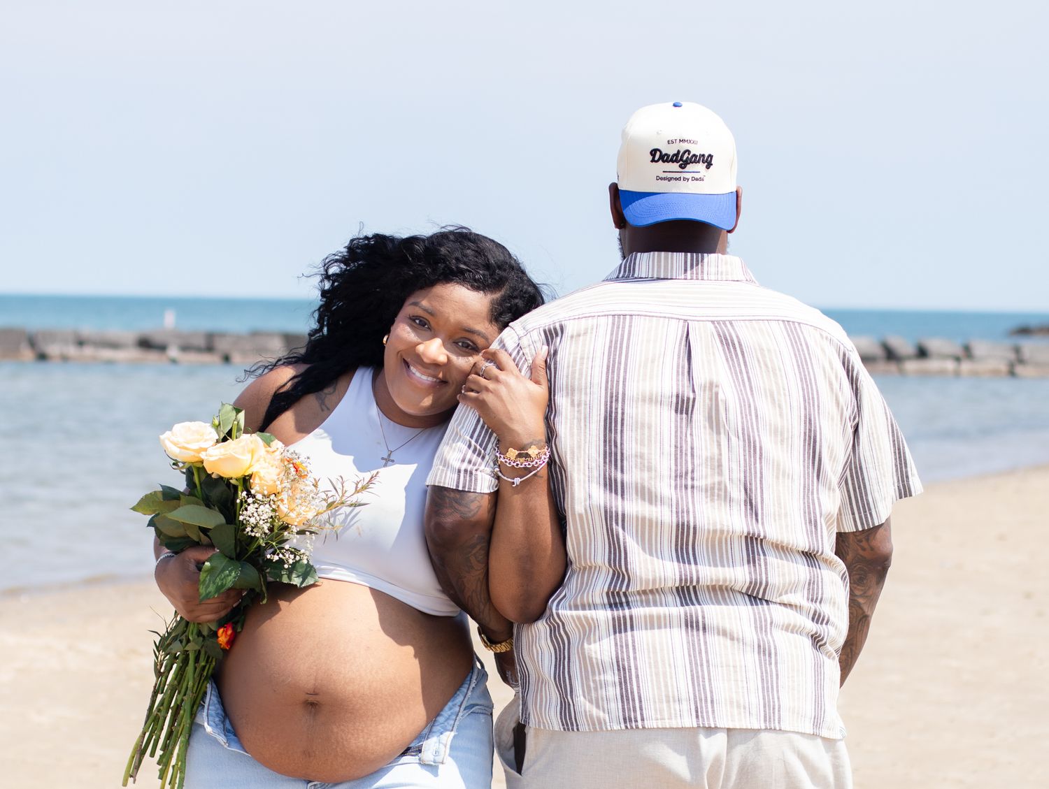 Maternity beach photo with expecting mother holding yellow roses.