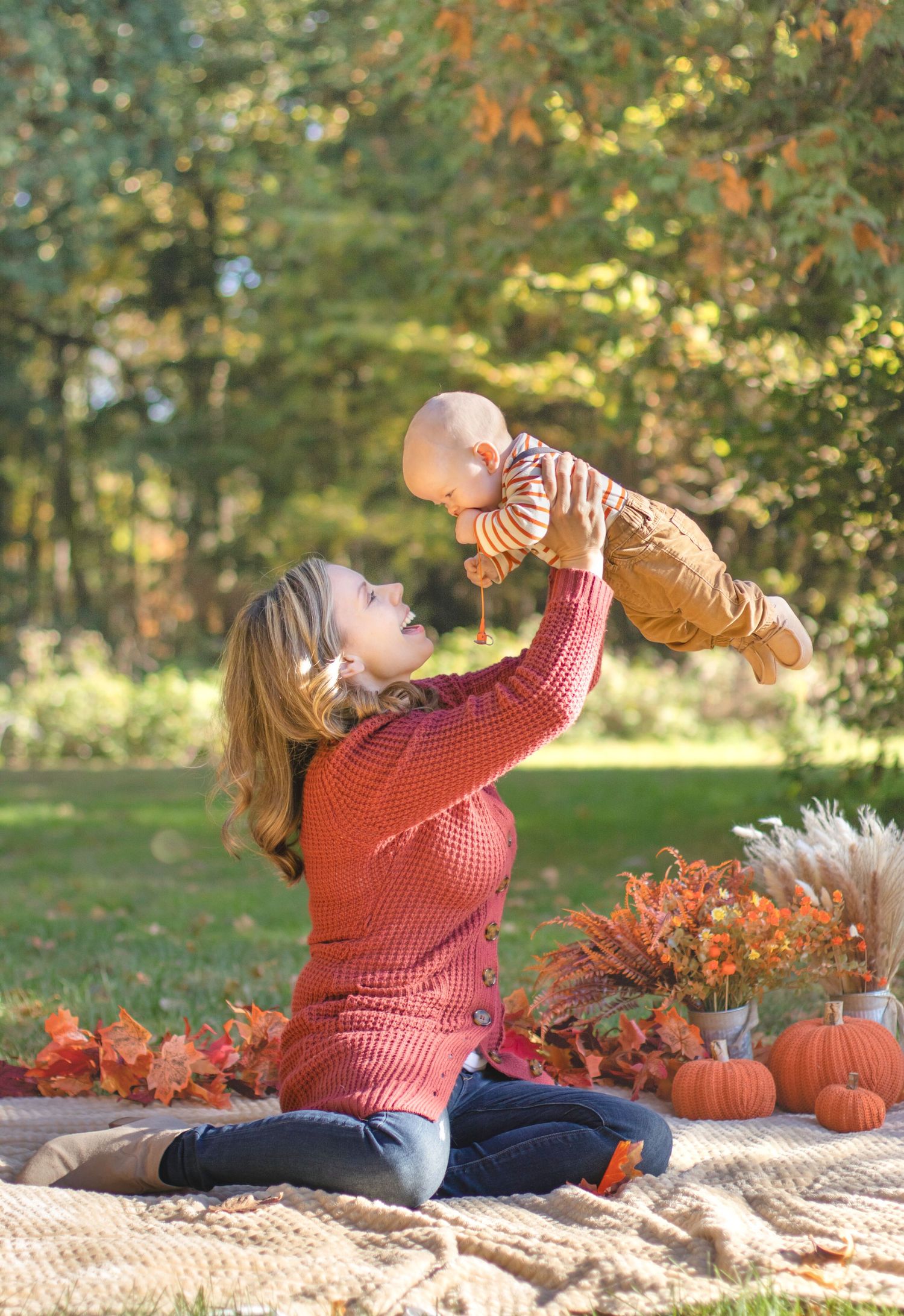 Autumn outdoor photo with pumpkins showing playful moment on picnic blanket.