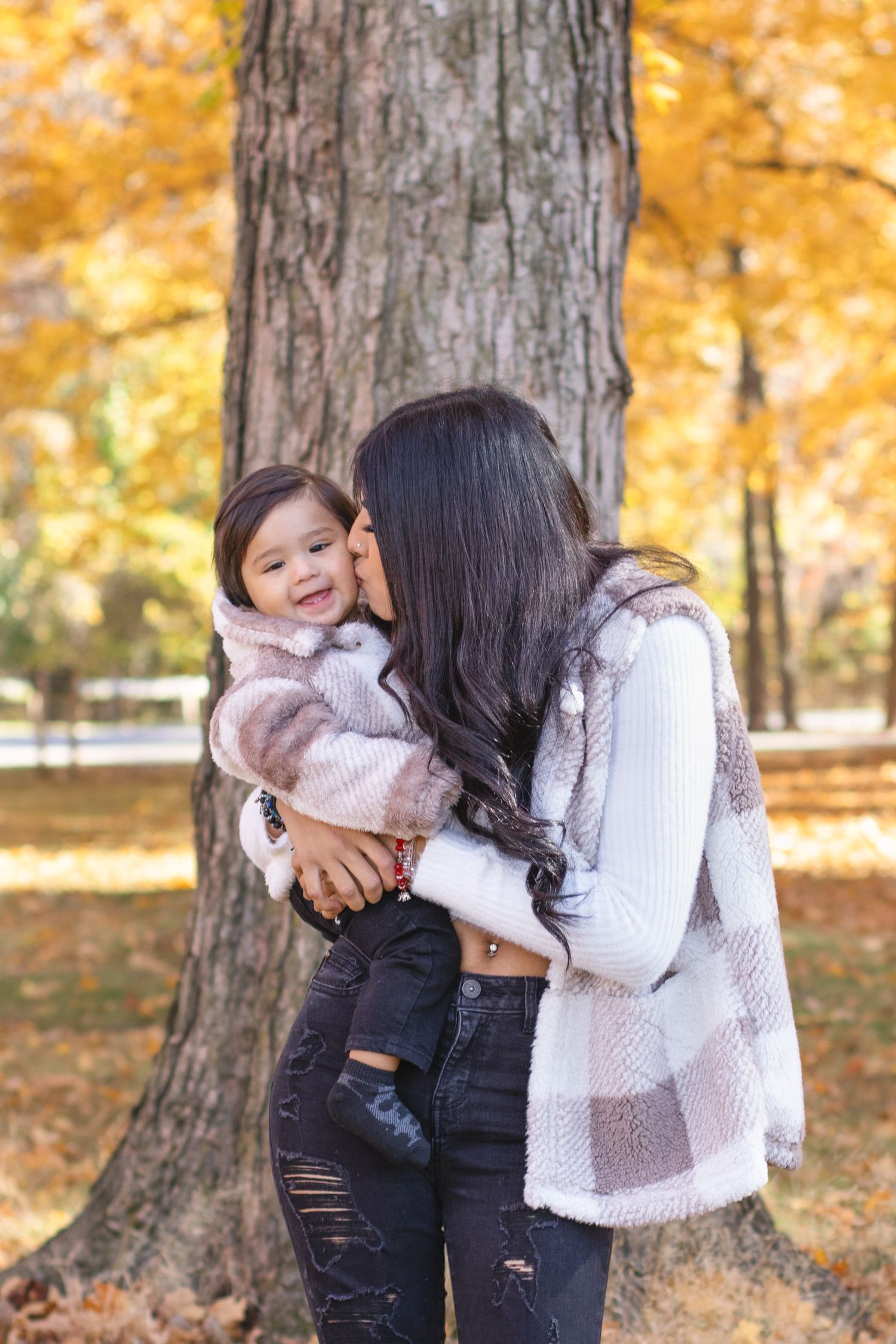 Parent and child share joyful moment together against fall foliage background.