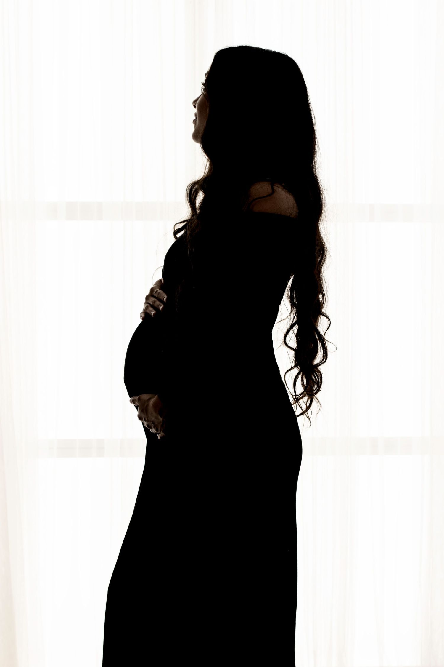 Silhouette of a figure with long wavy hair against a bright white background.