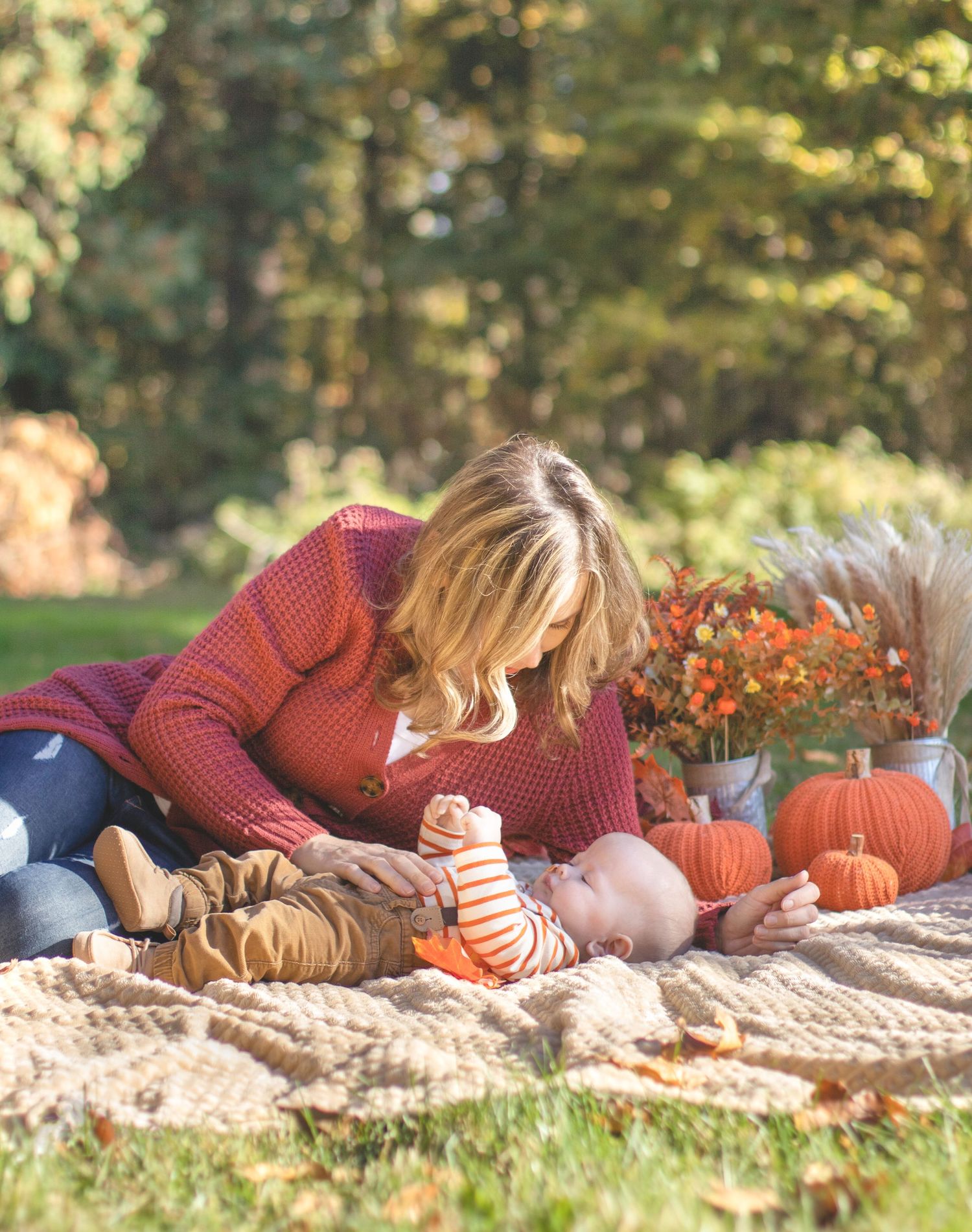 Cozy fall photoshoot on blanket with pumpkins and autumn decorations.
