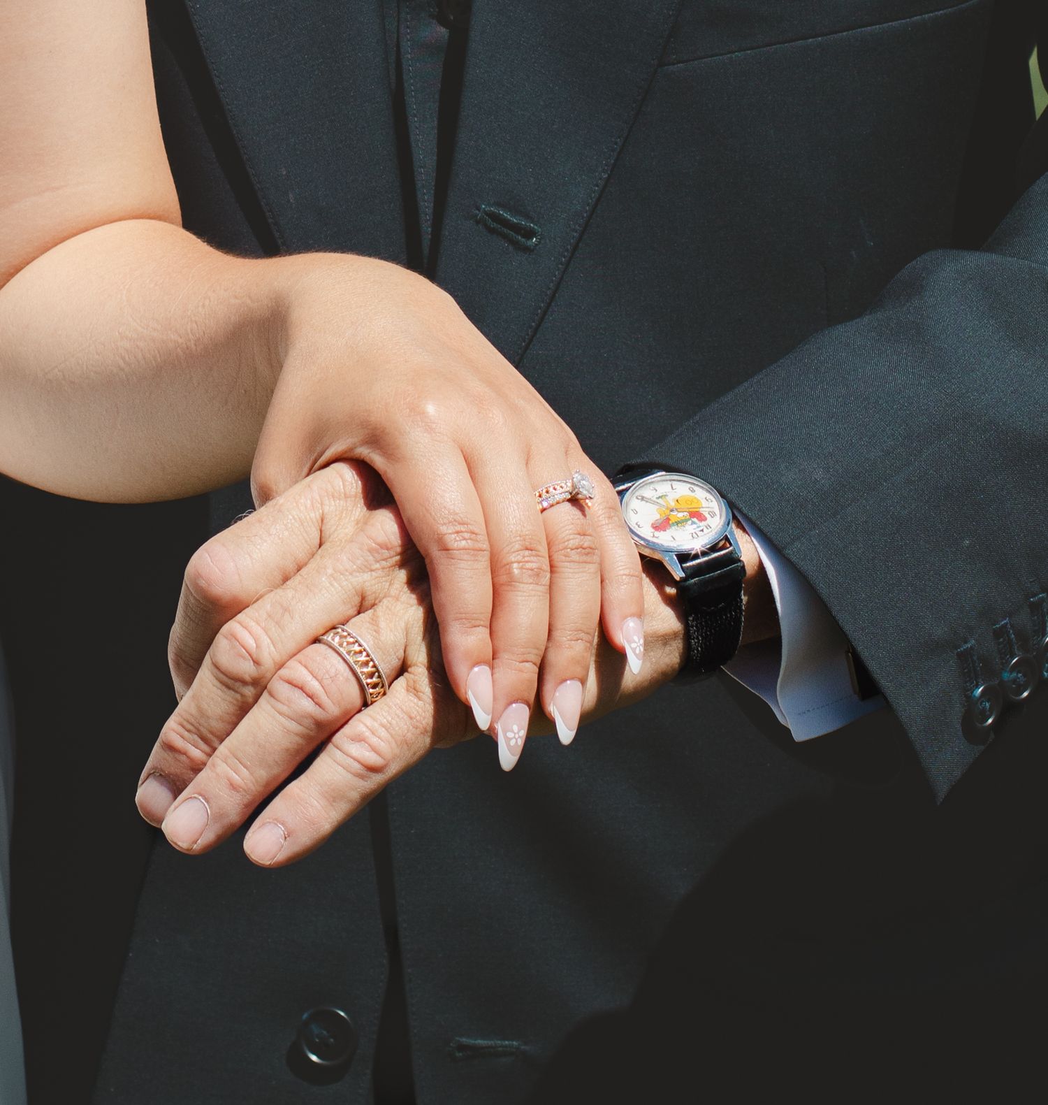 Close-up of hands showing wedding rings and jewelry during ceremony.