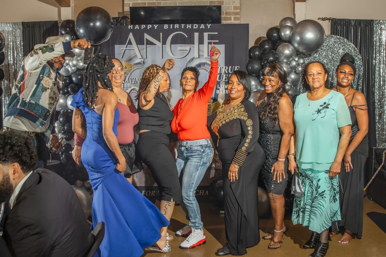 Group of women posing together at Angie's birthday party with black and silver balloon decorations.