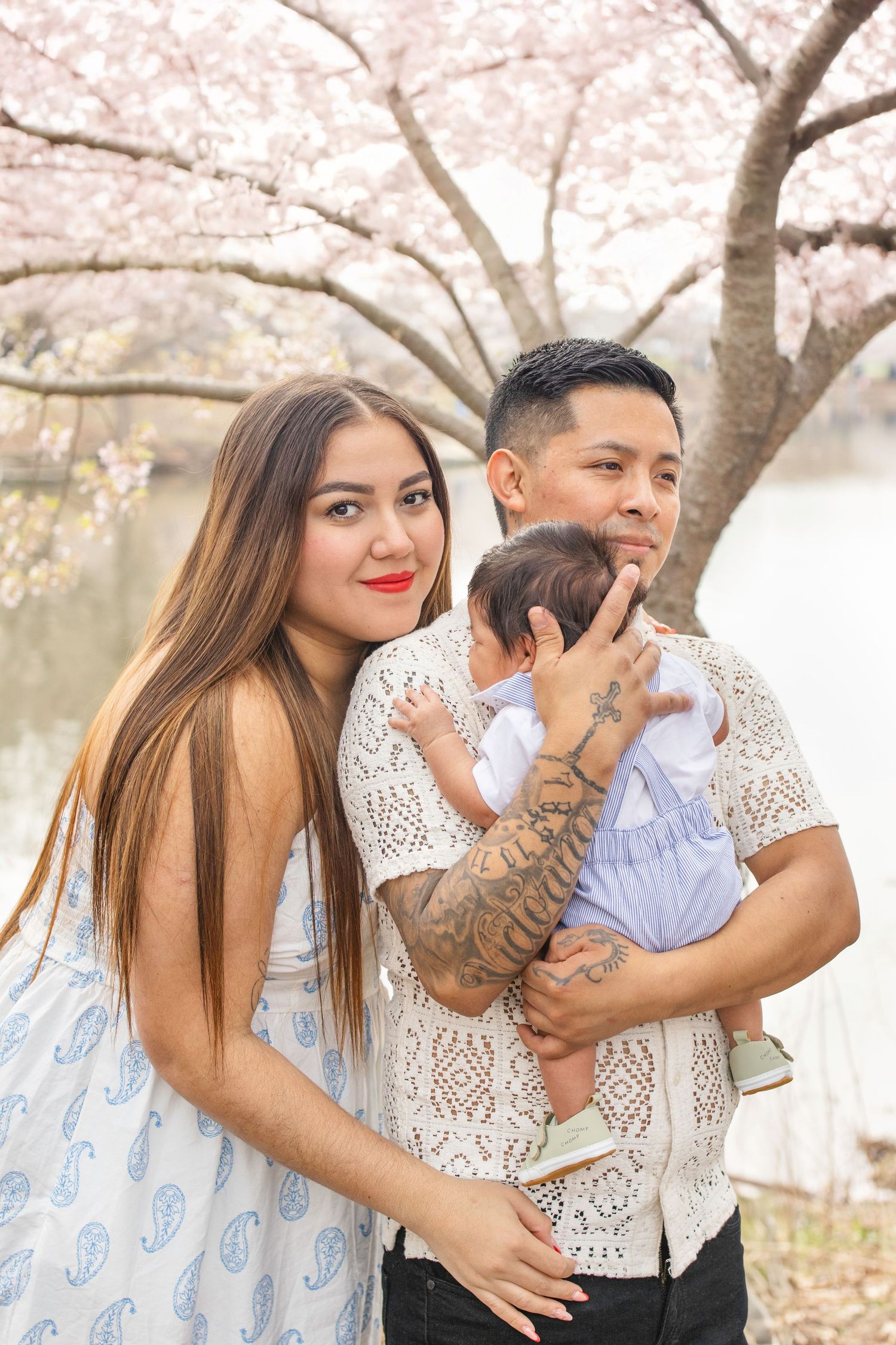 A family poses together under blooming cherry blossom trees on a spring day.