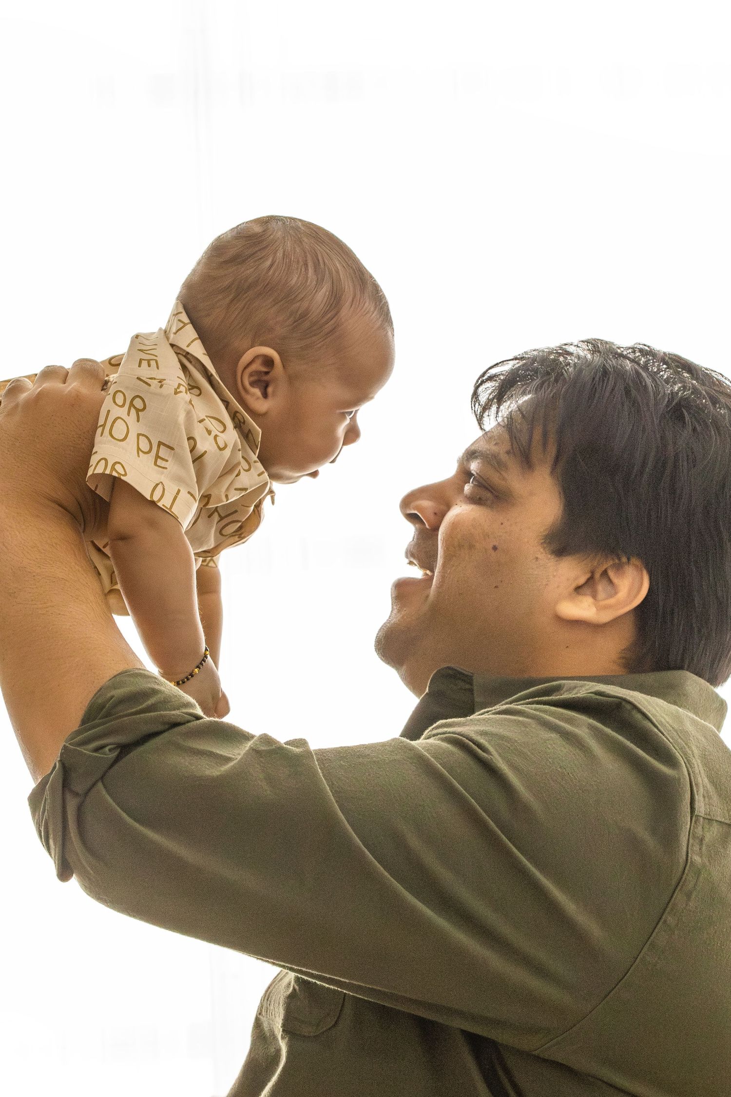 A sequence of photos showing a person lifting a baby up in the air against a white background.
