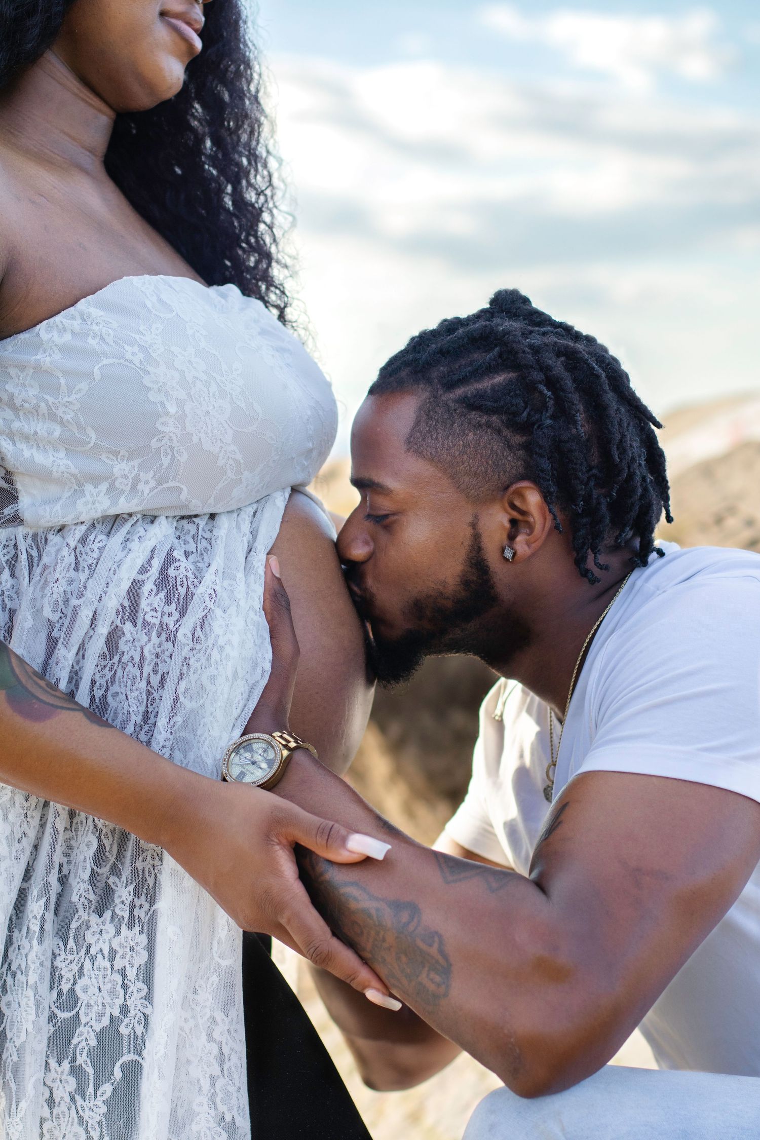 Intimate maternity photo of couple embracing outdoors during sunset.